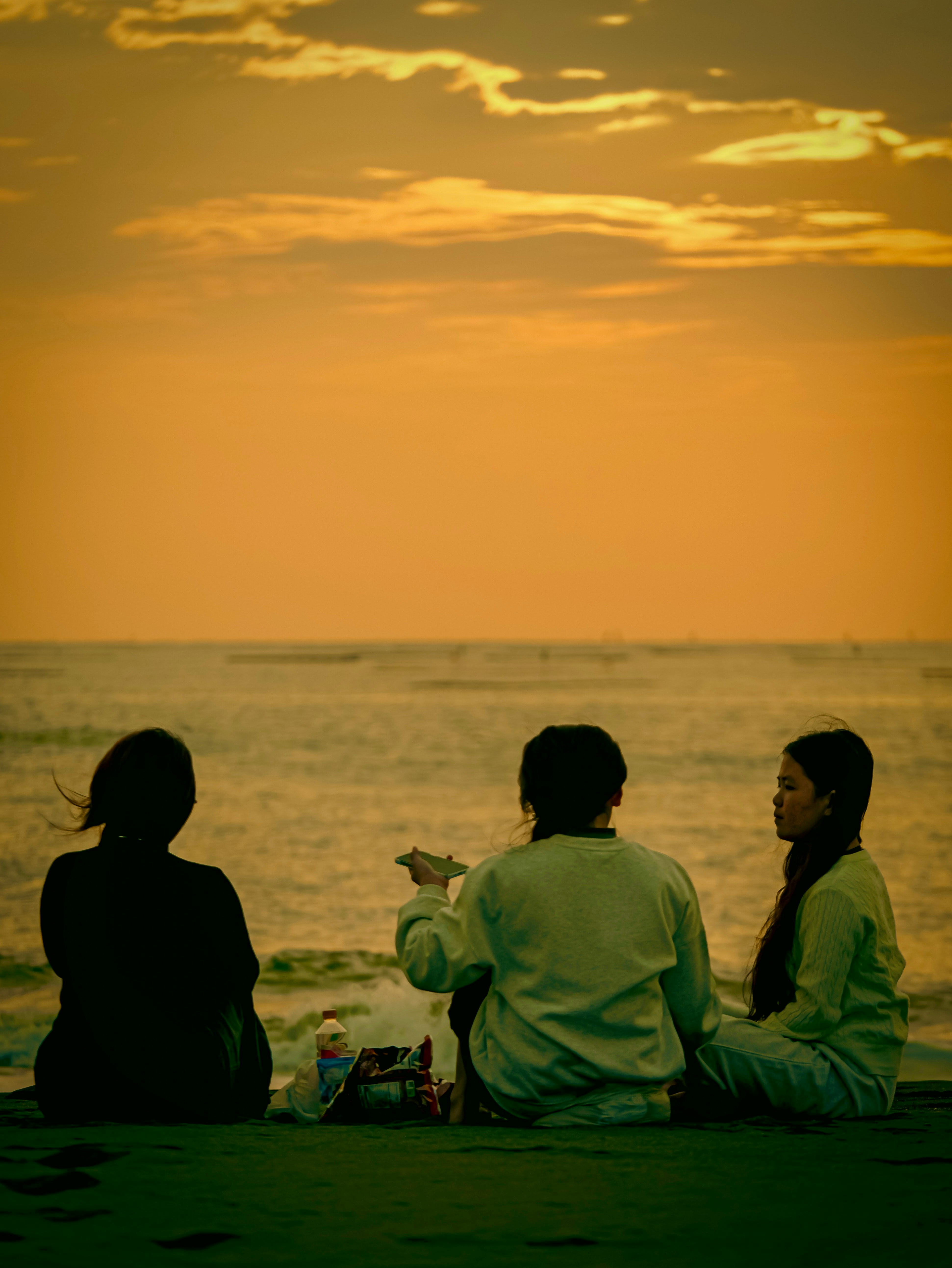 夕暮れの海辺で青春を語る友人たち