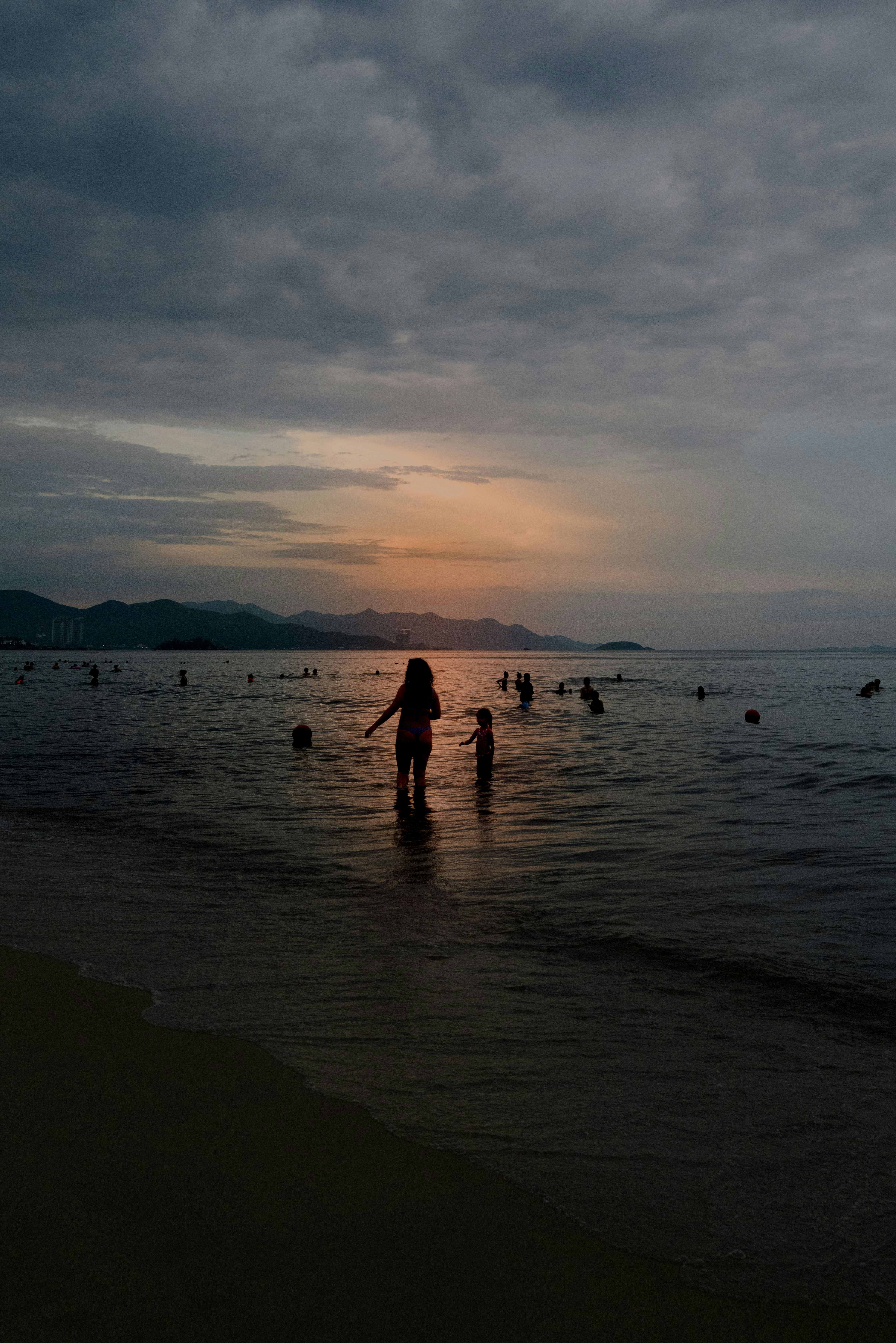 夕暮れの海辺でシルエットの人と波打ち際