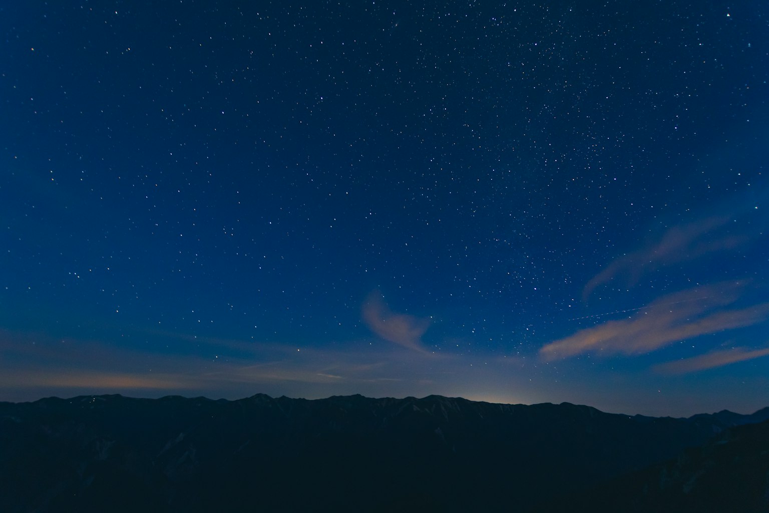 Langit malam berbintang dengan siluet gunung