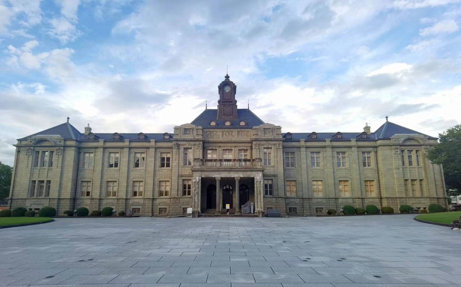 Fachada de un edificio histórico con césped verde y cielo azul de fondo