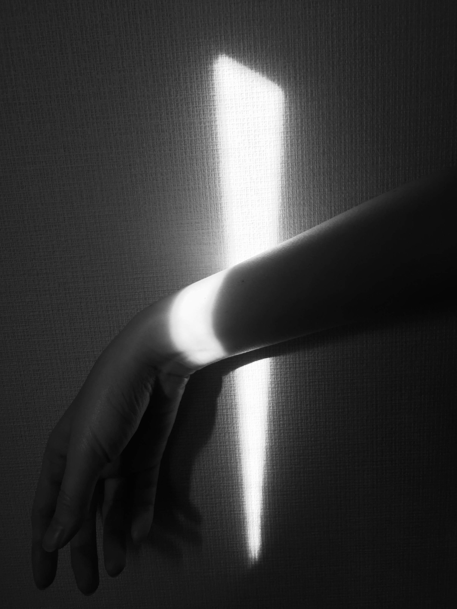 Image en noir et blanc d'une main avec un faisceau de lumière sur le poignet