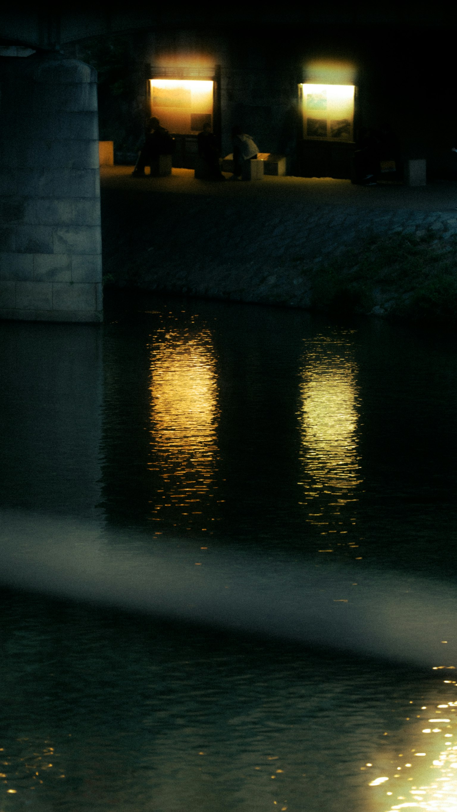 水面に映る光の反射と橋の柱の影
