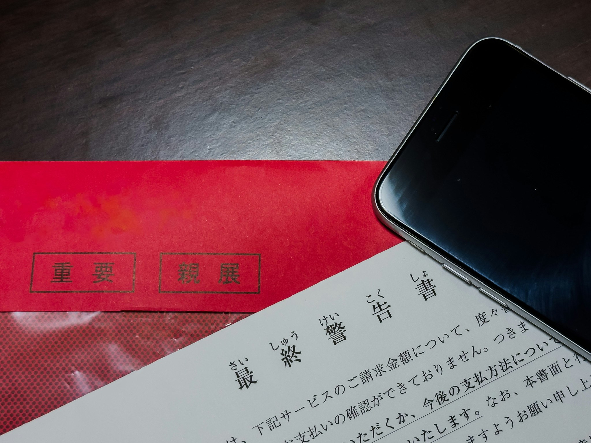 紅色信封旁的紙本信件文字與手機