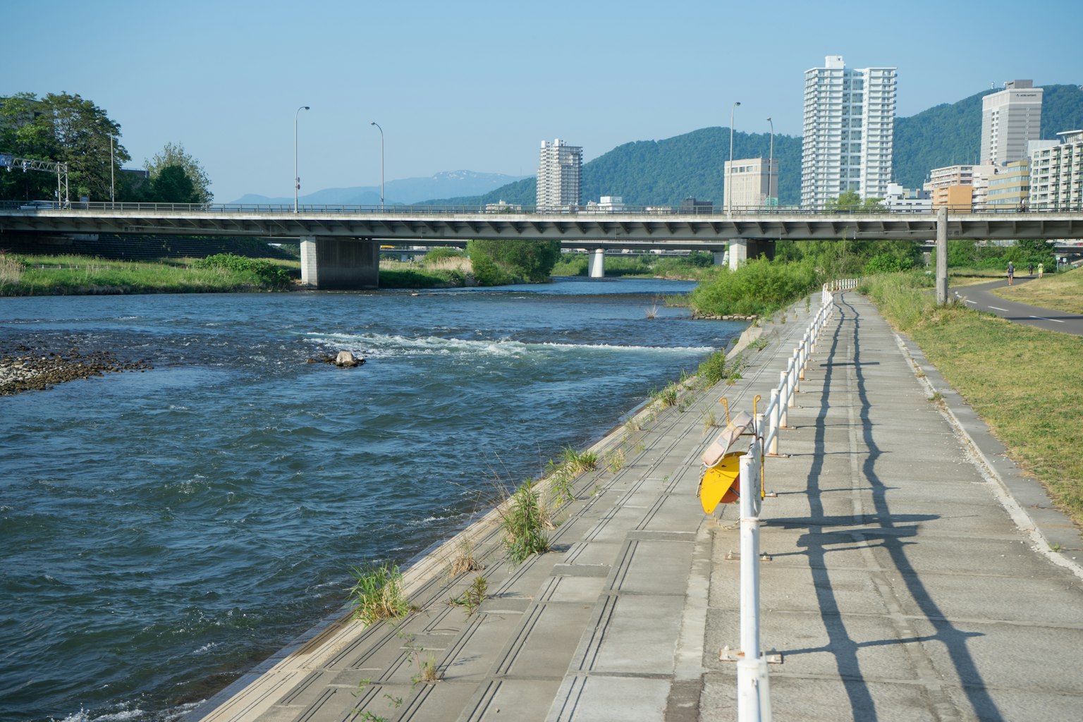 Scenic riverside walkway with modern buildings in the background