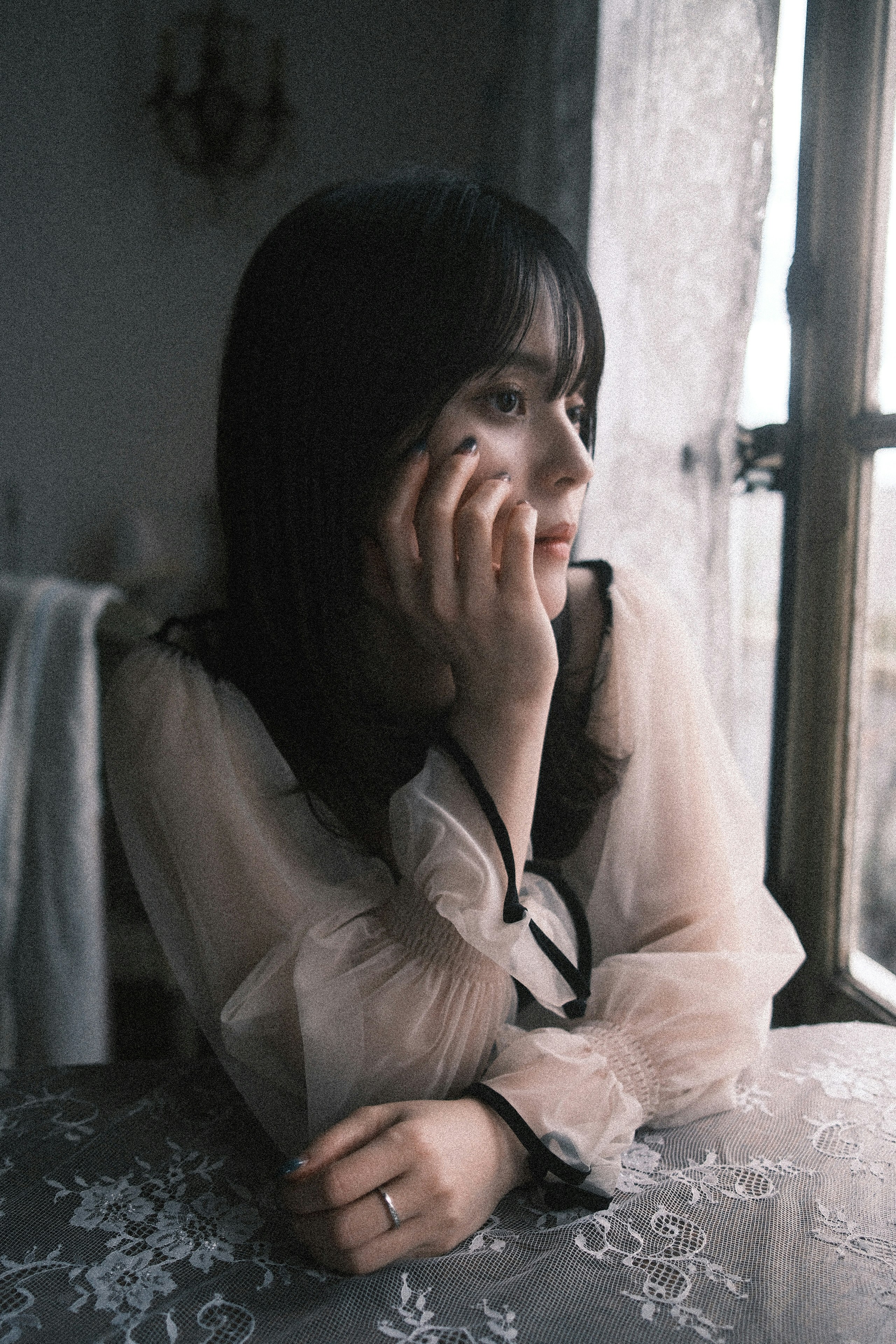 窓辺で頬に手を当てる女性のポートレート