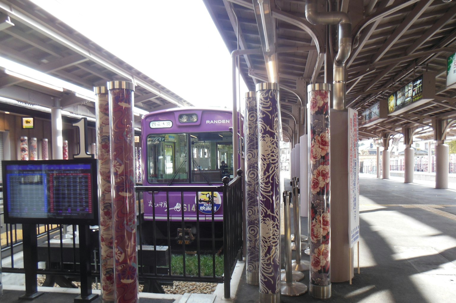 View of a station with a purple train parked Decorative colorful pillars are visible
