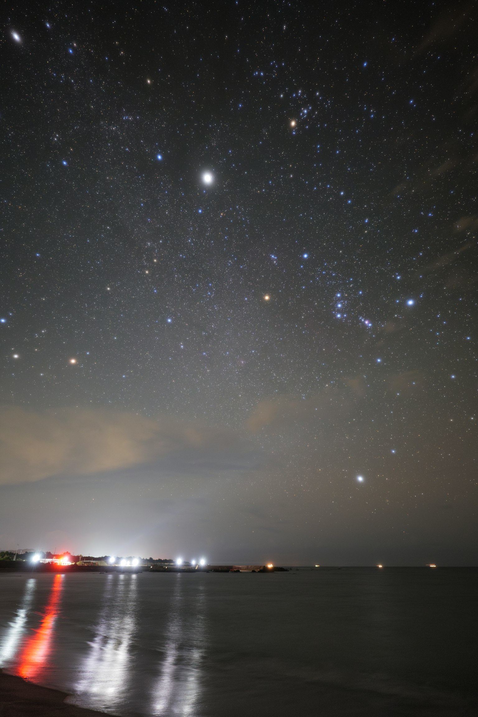 Cielo notturno pieno di stelle su una spiaggia stelle brillanti e luci di barche in lontananza