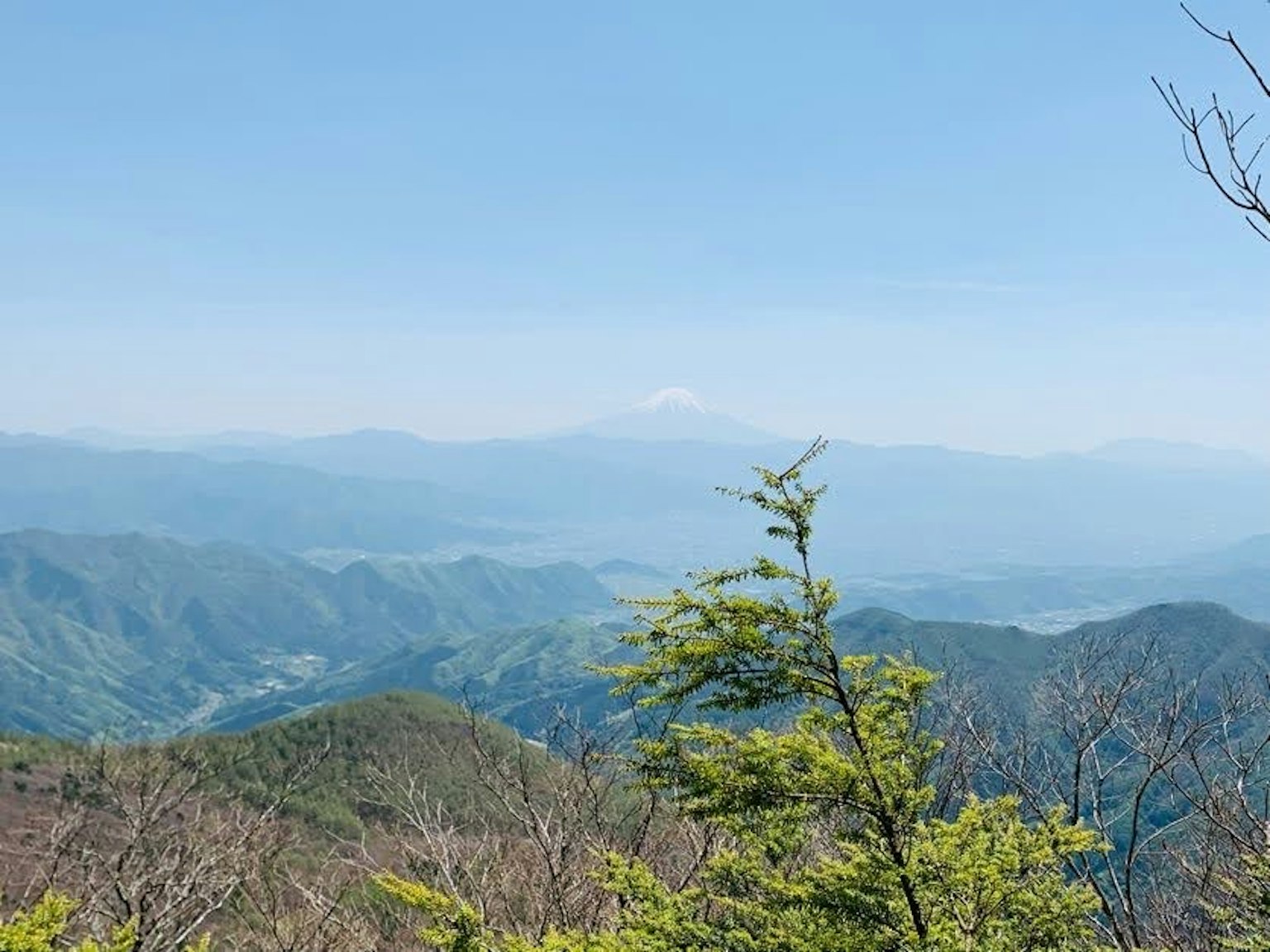 Scenic view of mountains under a blue sky with Mount Fuji in the distance
