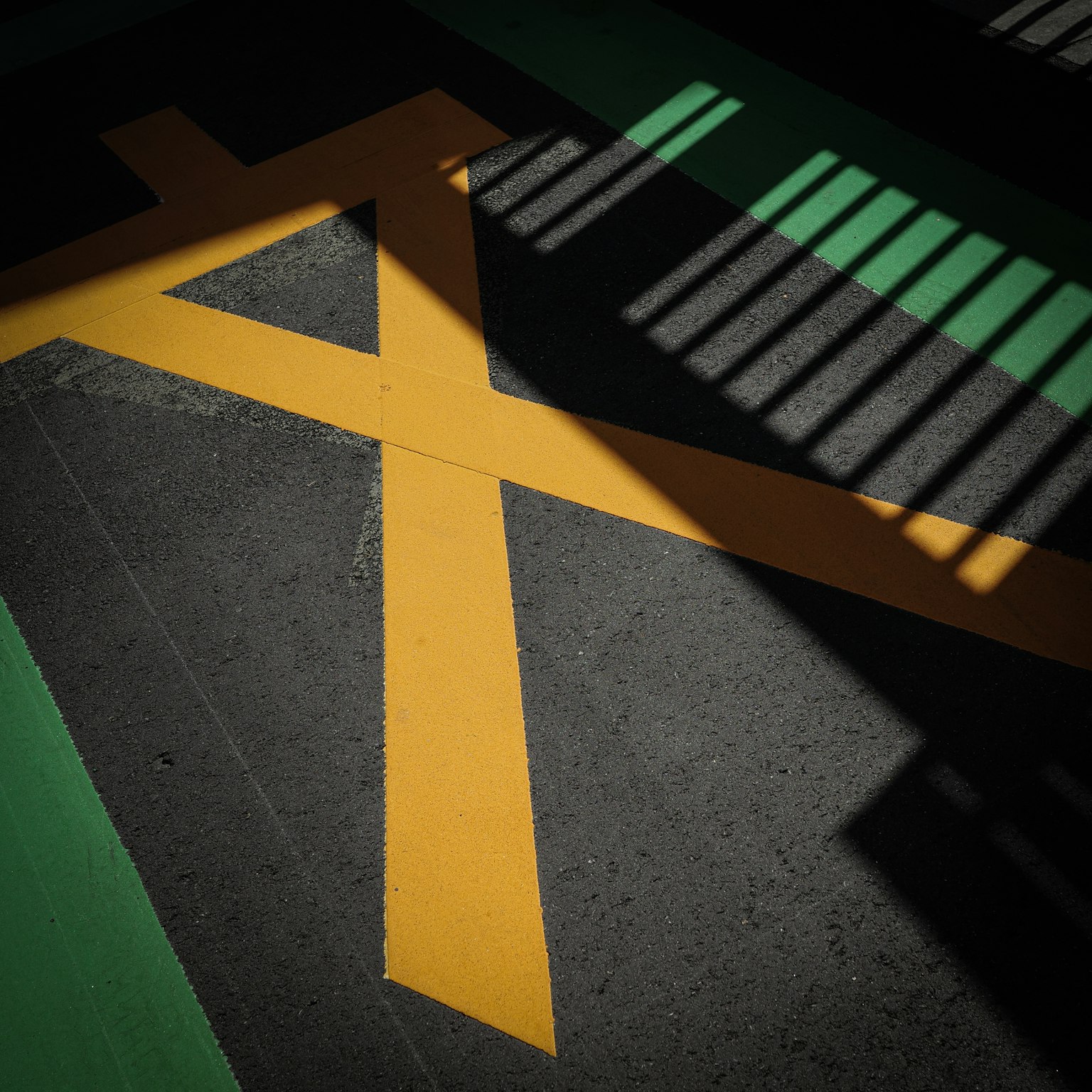 Marquages jaunes sur le sol d'un parking avec des ombres contrastantes