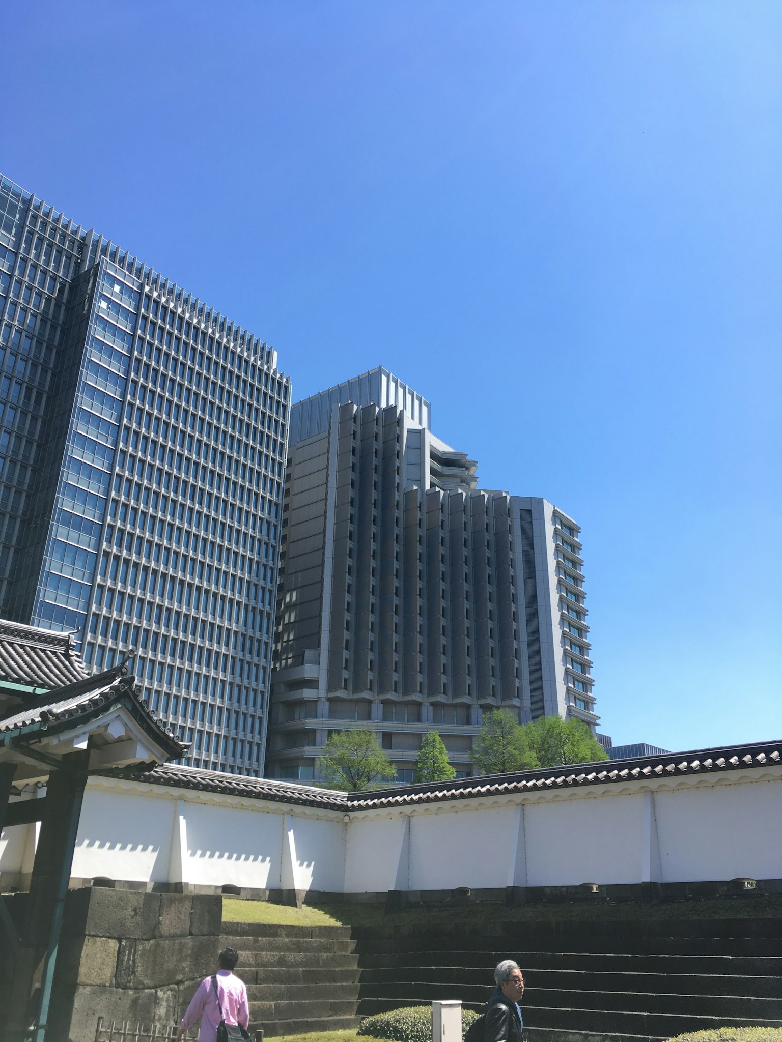 Una vista de rascacielos contra un cielo azul con arquitectura japonesa tradicional en primer plano