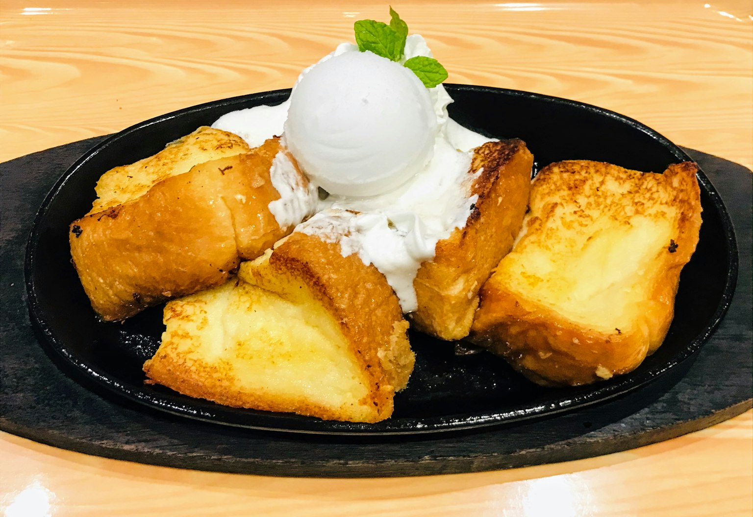 จานขนมปังทอดร้อนกับไอศกรีมวนิลลาและครีมฟู