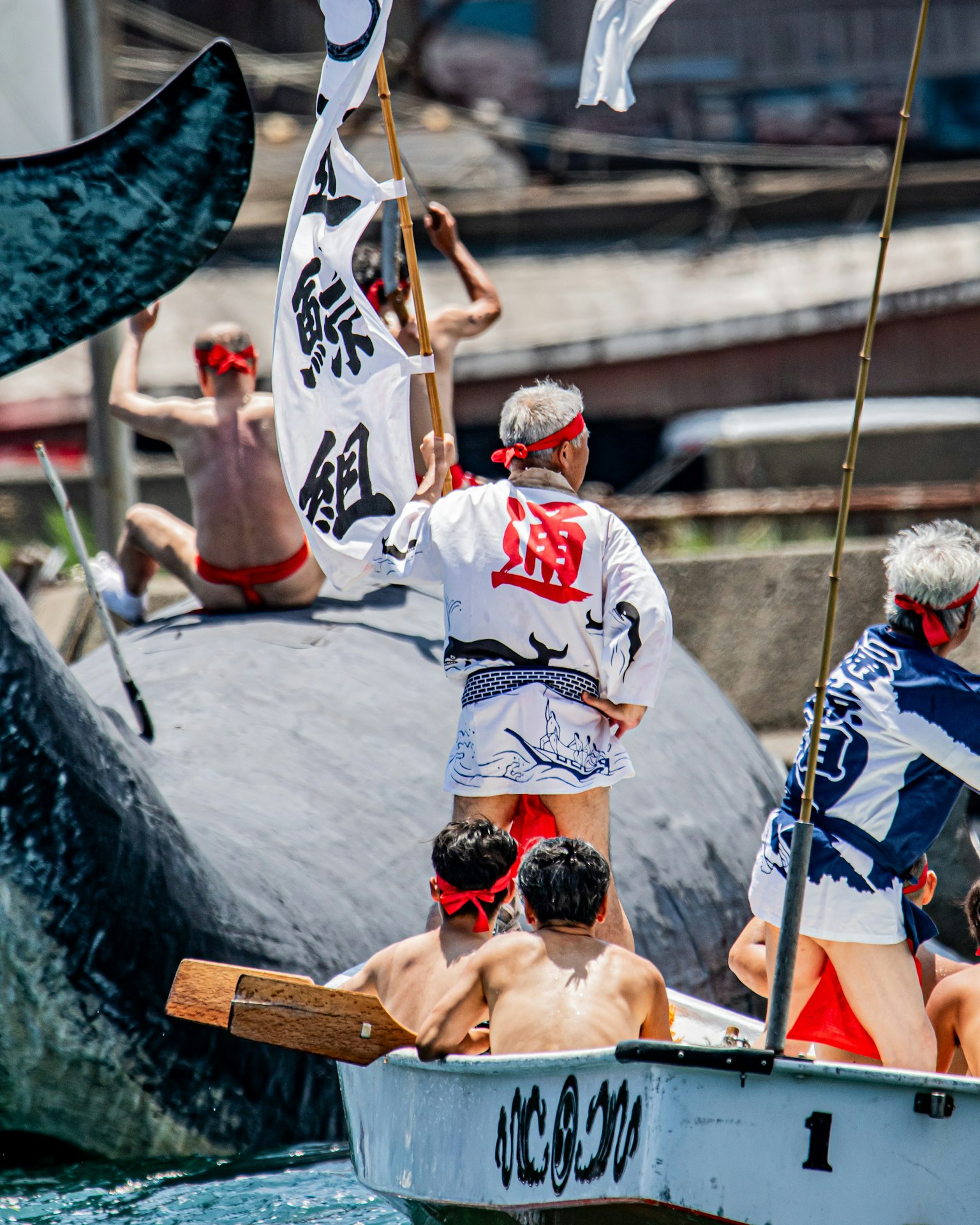 Persone in abiti tradizionali su una barca durante un festival di caccia alle balene