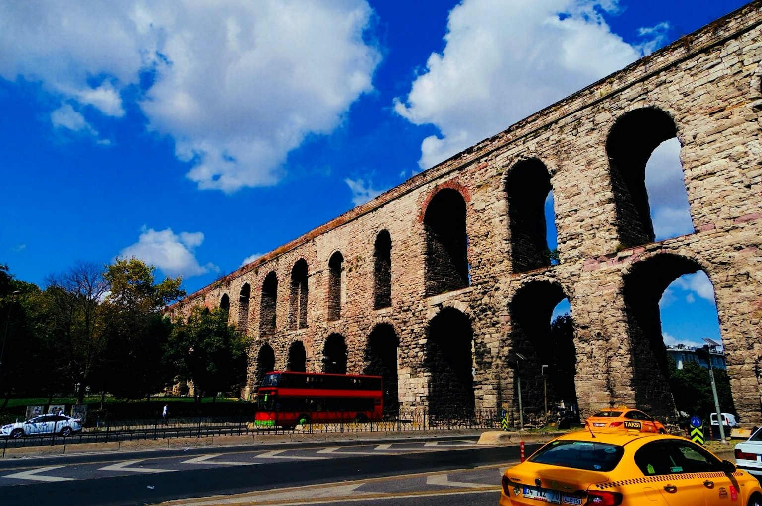 Ancient stone aqueduct arches in Istanbul against a bright blue sky