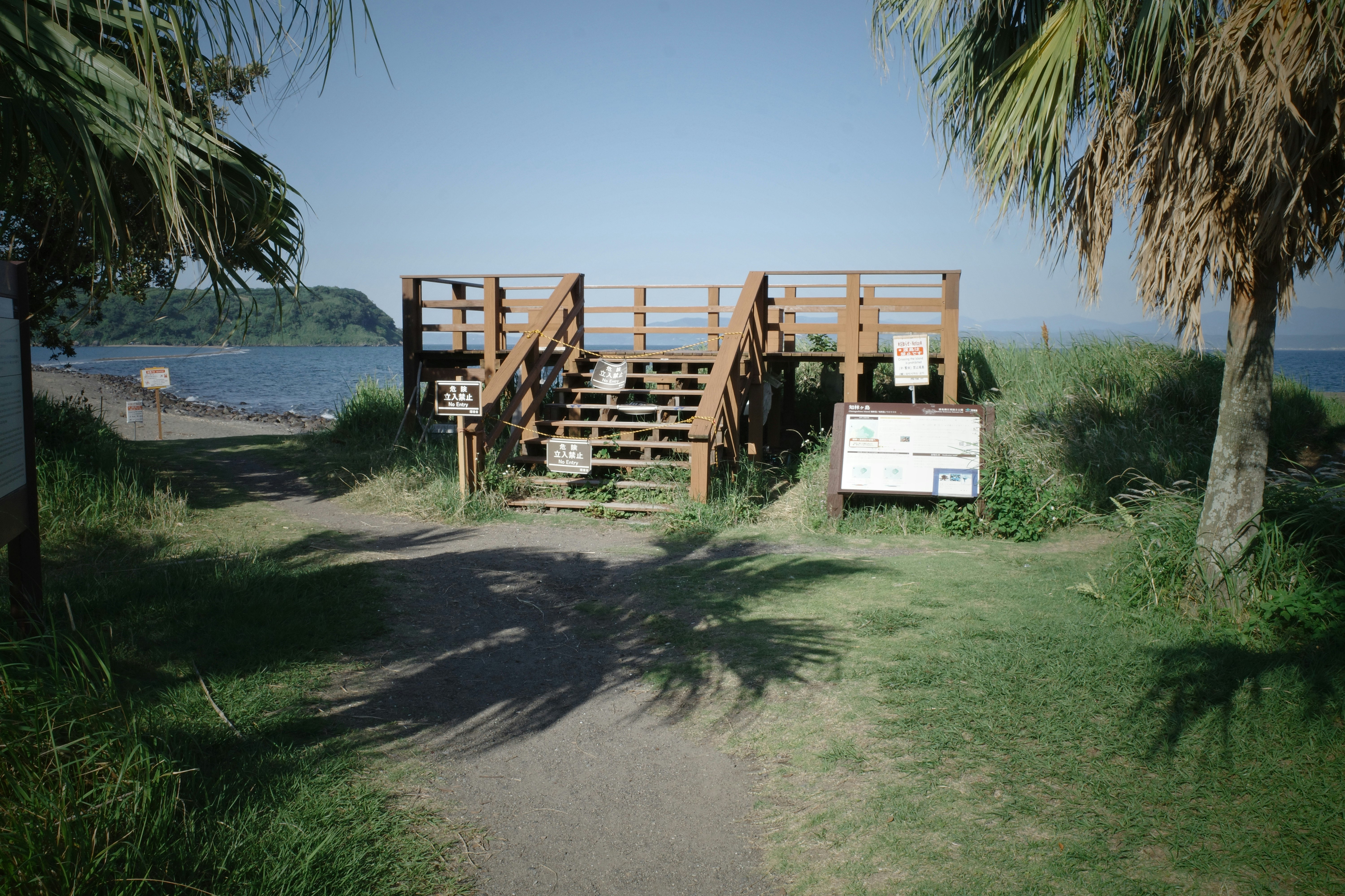 wooden benches and a sign on a grassy seaside area