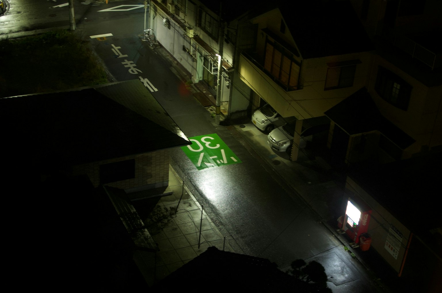 Vista nocturna de una calle con un letrero verde 30 iluminado