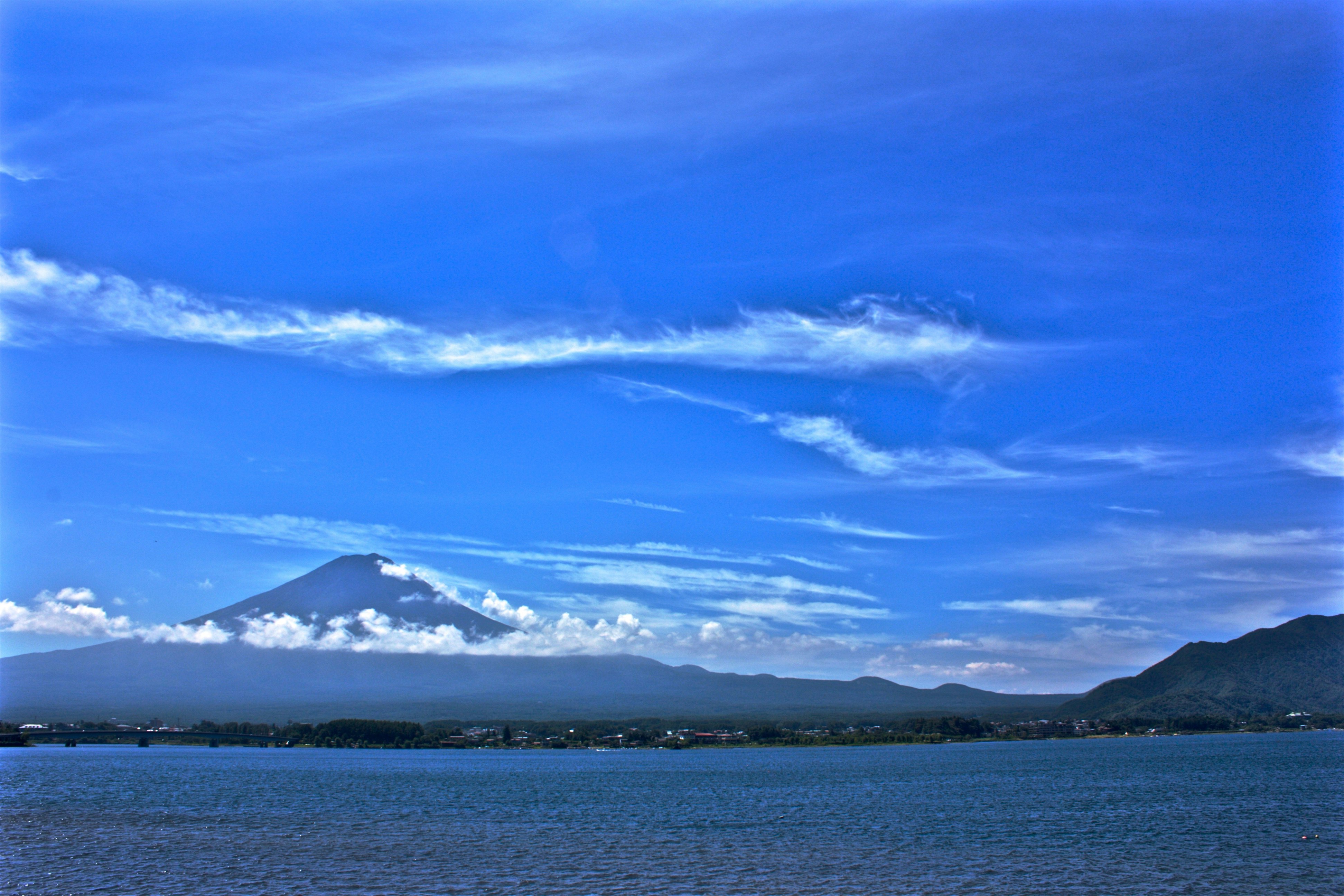 海面と水平線、遠くに山並みが望める青空の風景