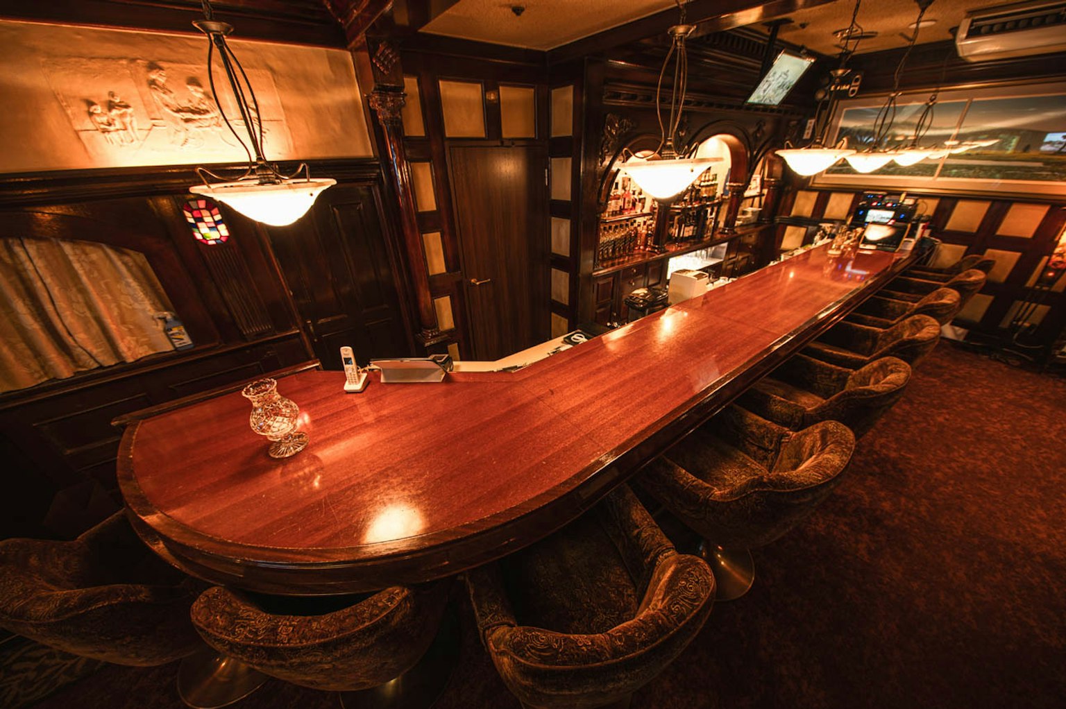 Interior de un bar con un largo mostrador de madera y asientos cómodos