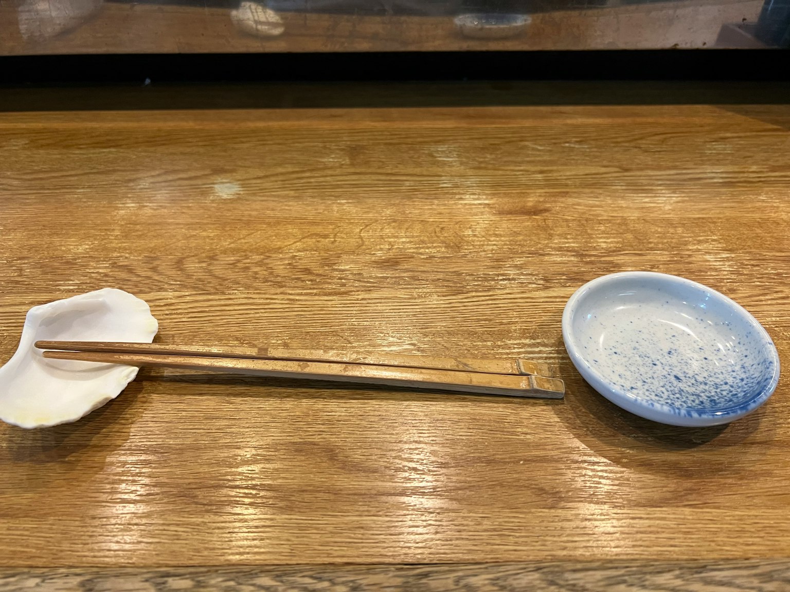 Plat blanc et assiette bleue avec des baguettes sur une table en bois