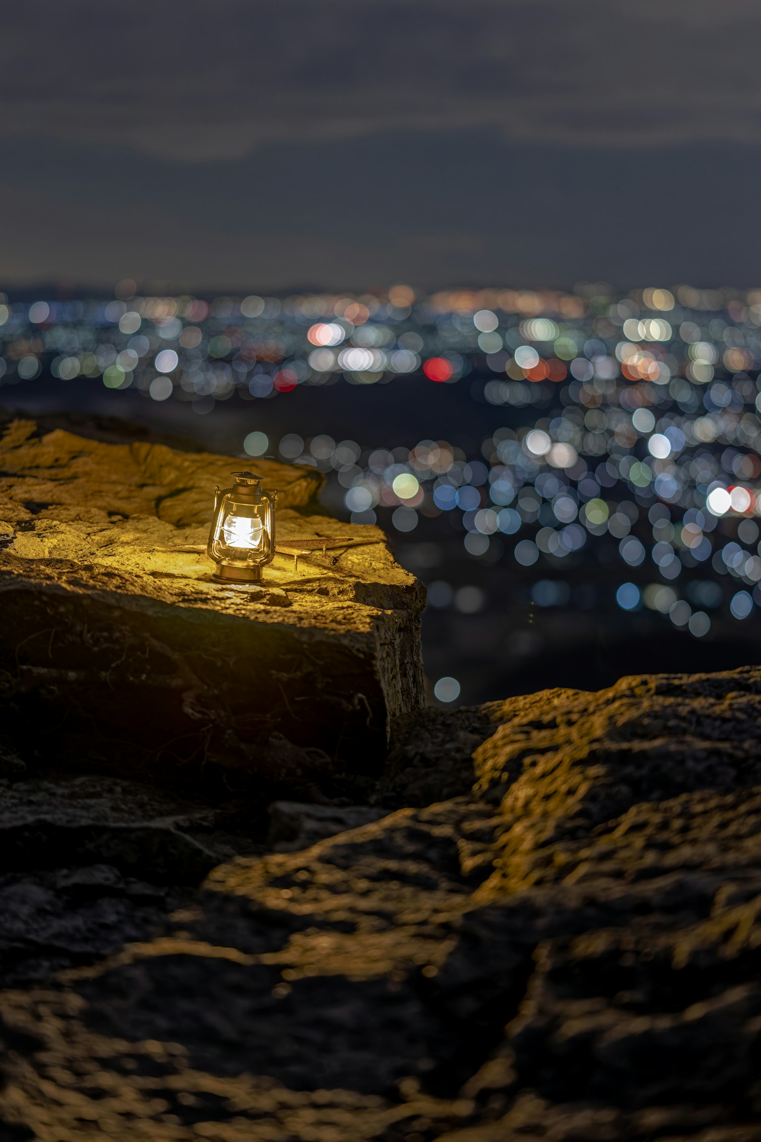 Candela su una roccia con luci della città sullo sfondo