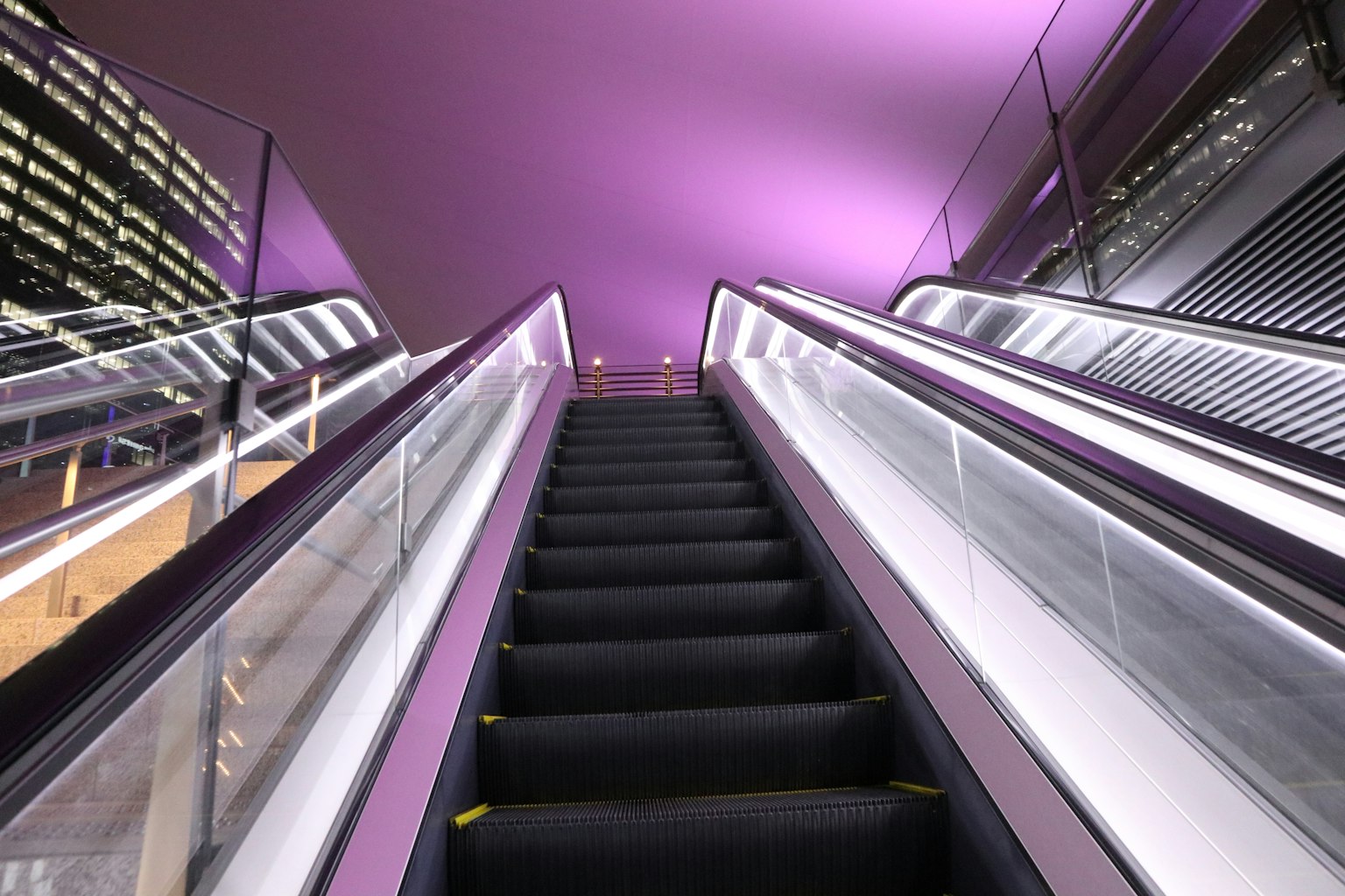 Vista di una scala mobile dal basso con illuminazione viola