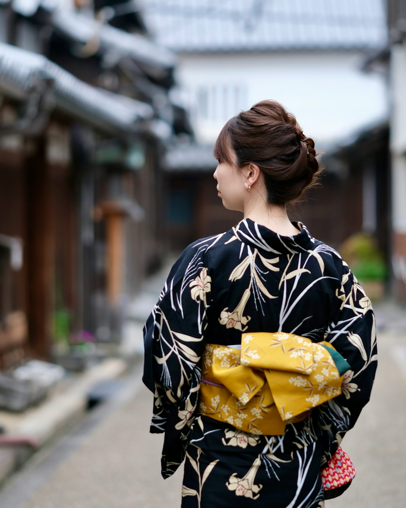 Một người phụ nữ trong bộ kimono truyền thống đi bộ qua phố cổ