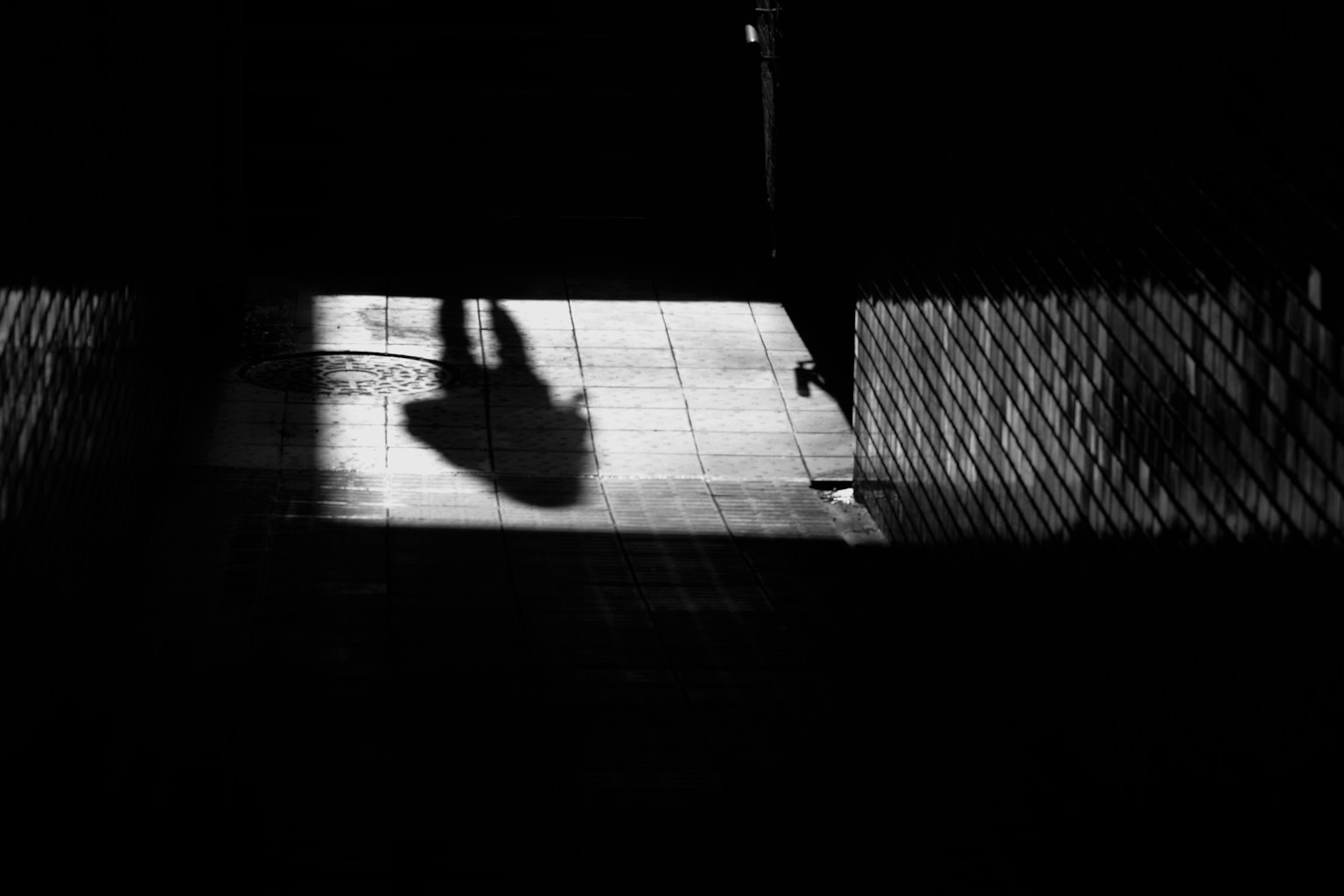 Silueta de una persona en un pasillo oscuro con luz en el suelo