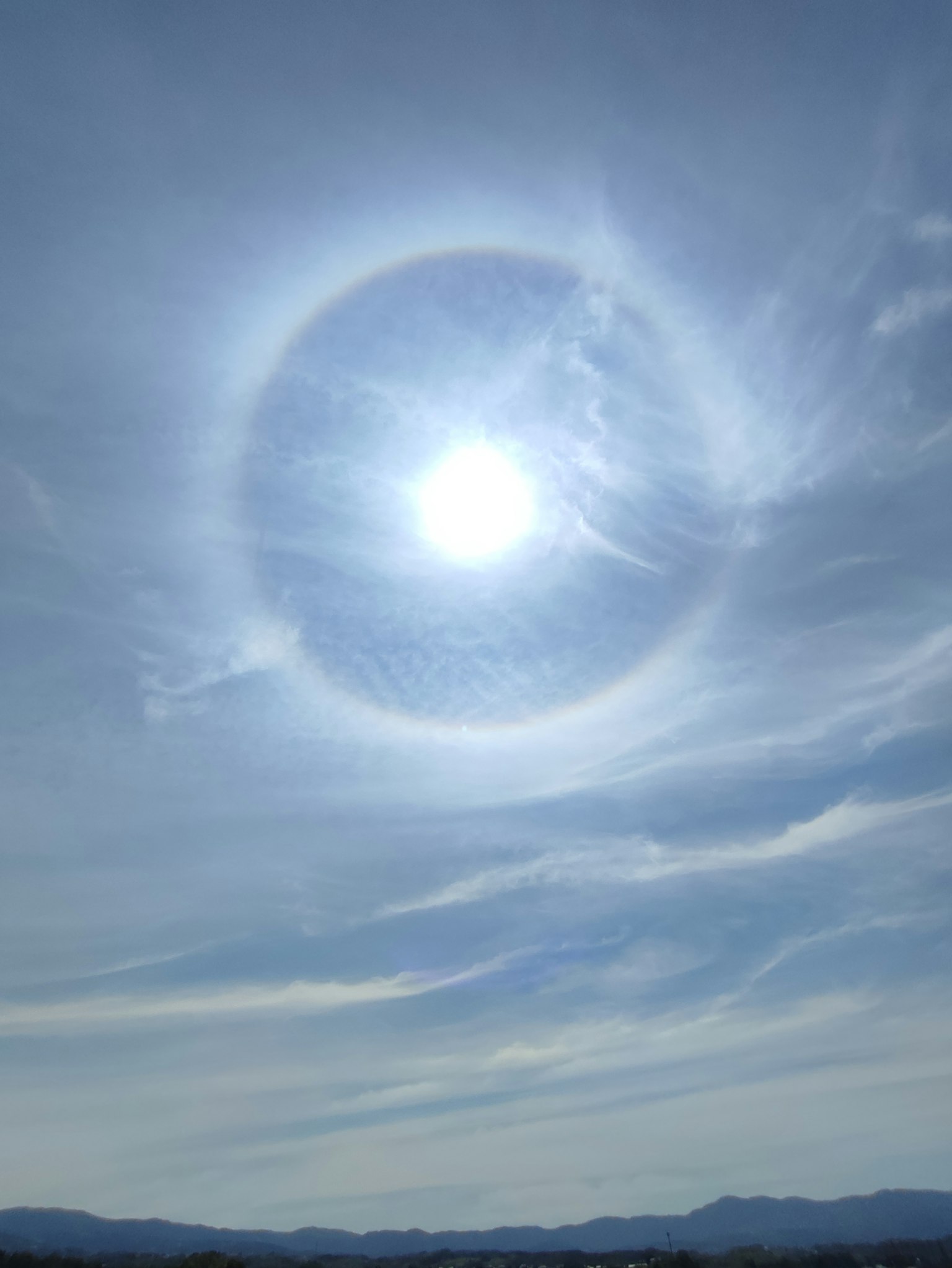 Eine helle Sonne umgeben von einem Halo in einem klaren blauen Himmel