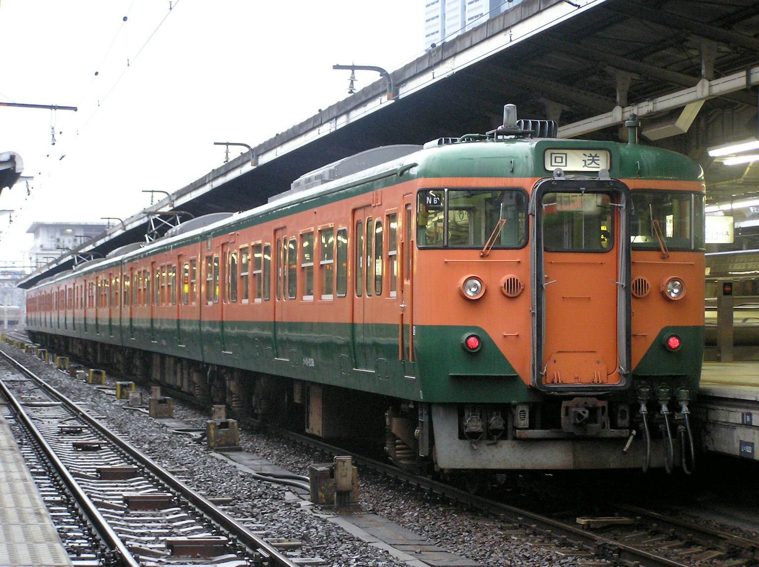 Treno arancione e verde parcheggiato in una stazione