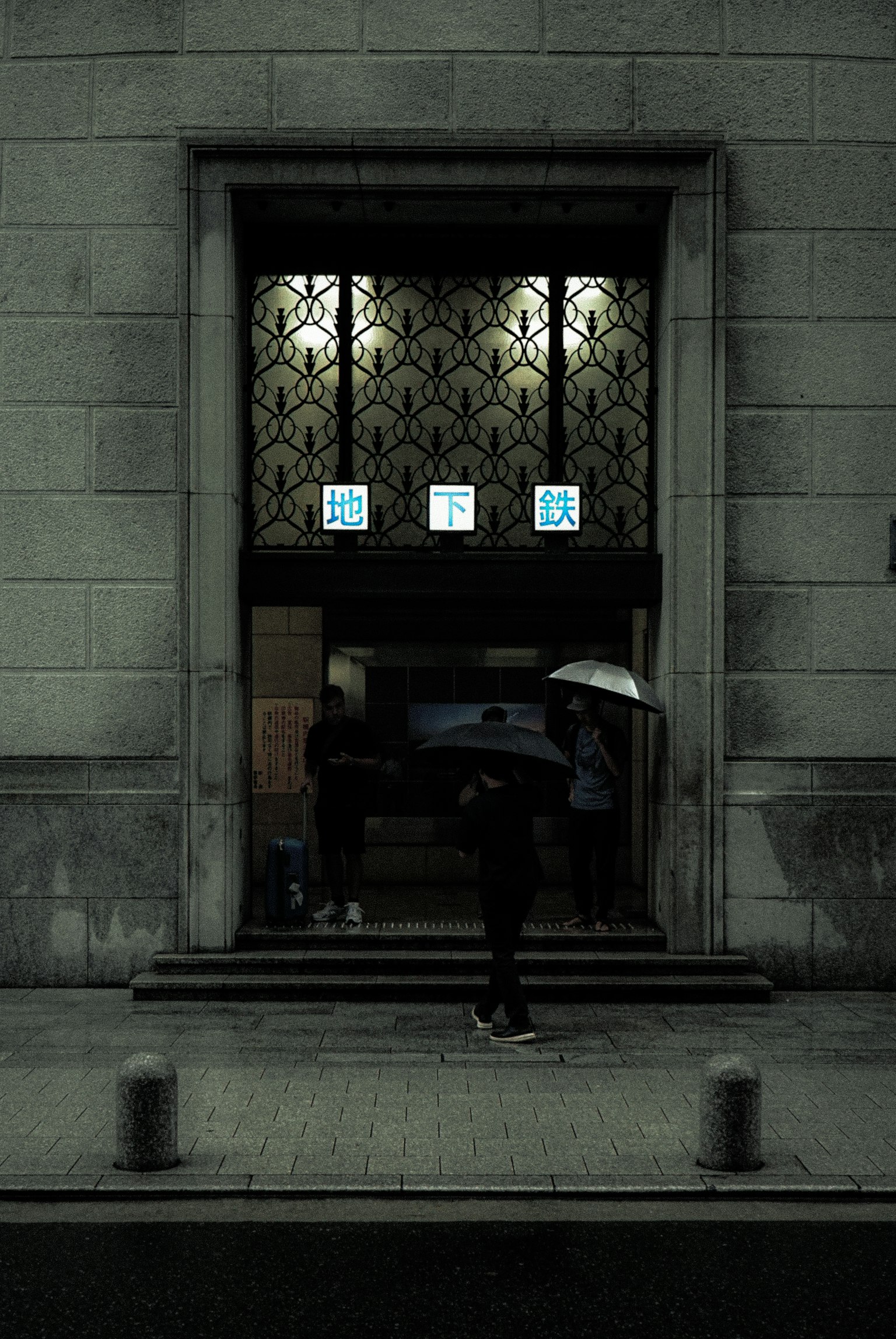 在黑暗街道上，一個拿著傘的人走在美麗建築的入口前