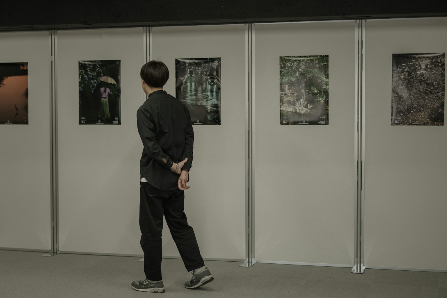 검은 옷을 입고 갤러리에서 사진을 감상하는 남자 벽에 전시된 사진