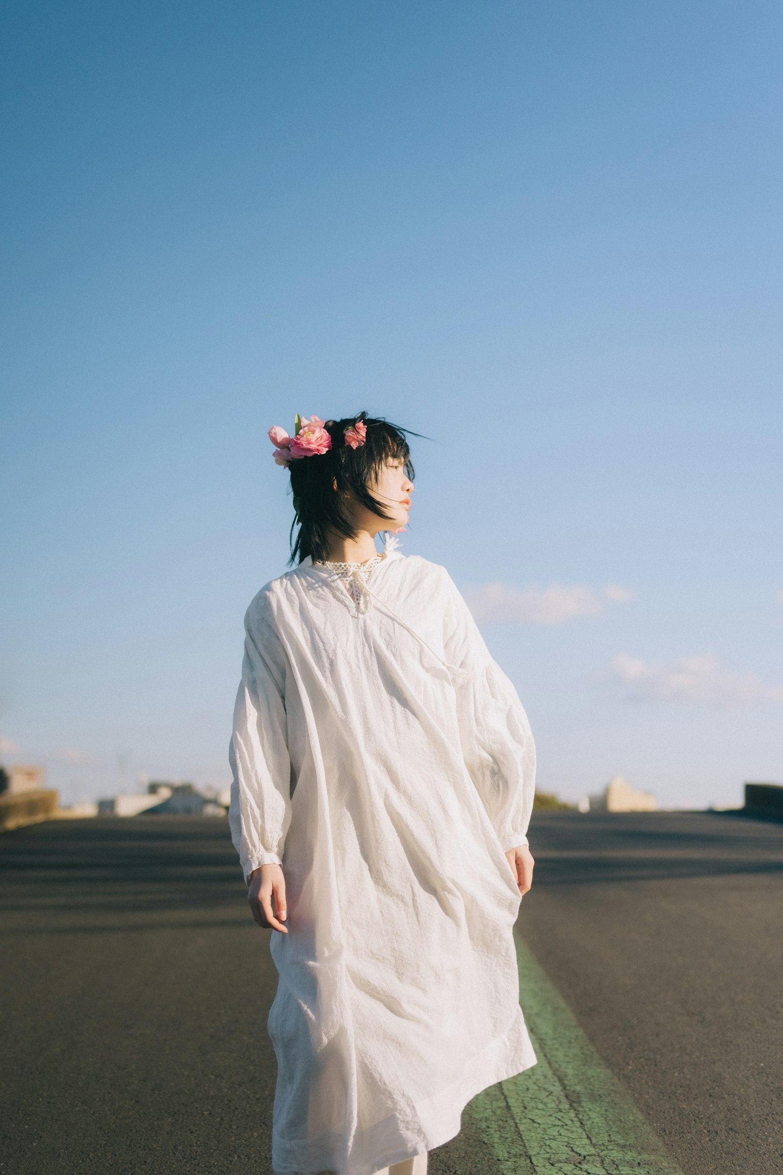 白いドレスを着た女性が青い空の下で後ろを向いている