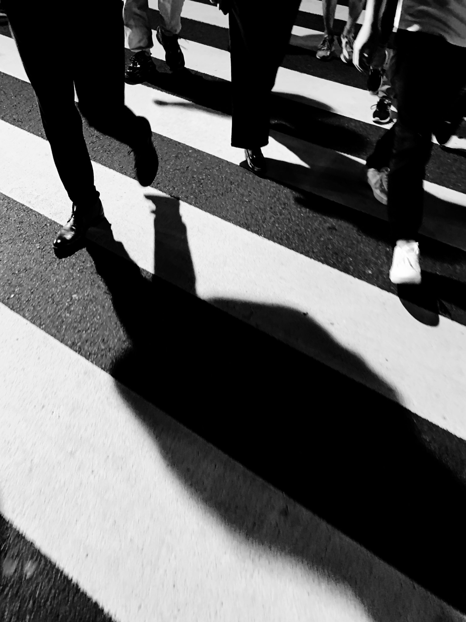 Bayangan orang yang berjalan di zebra cross hitam putih