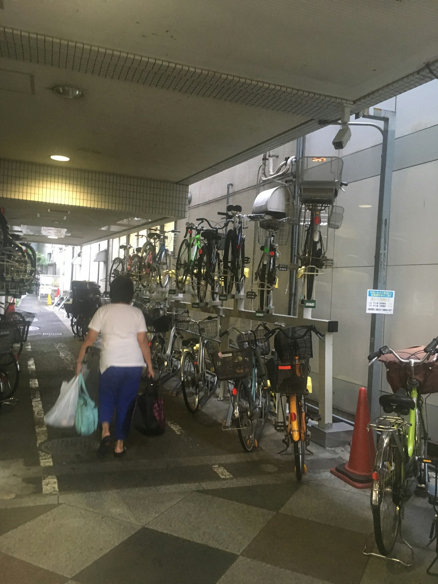 Una mujer caminando con bolsas de compras en un área de estacionamiento de bicicletas llena de bicicletas