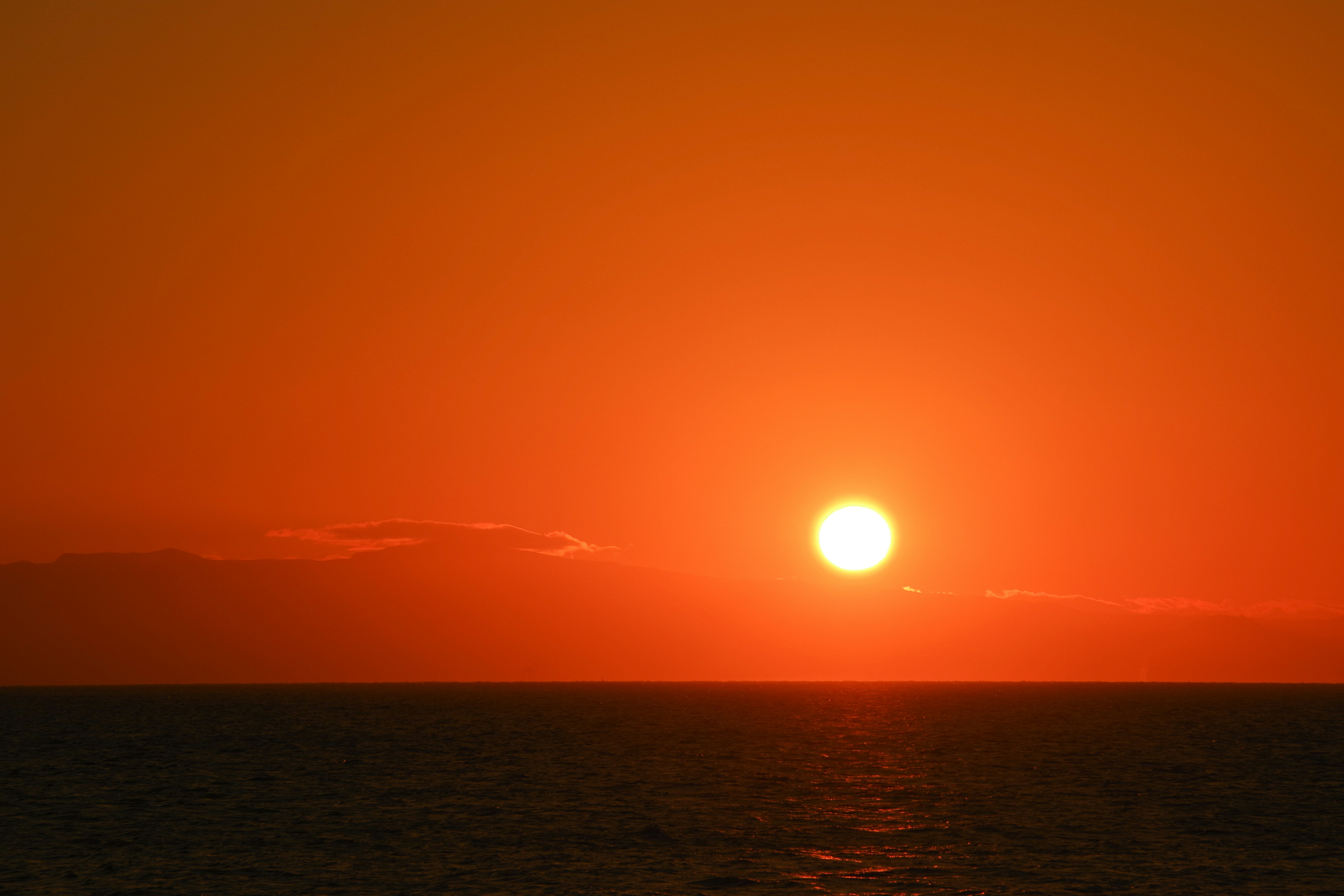 夕日に照らされる海面と水平線の光