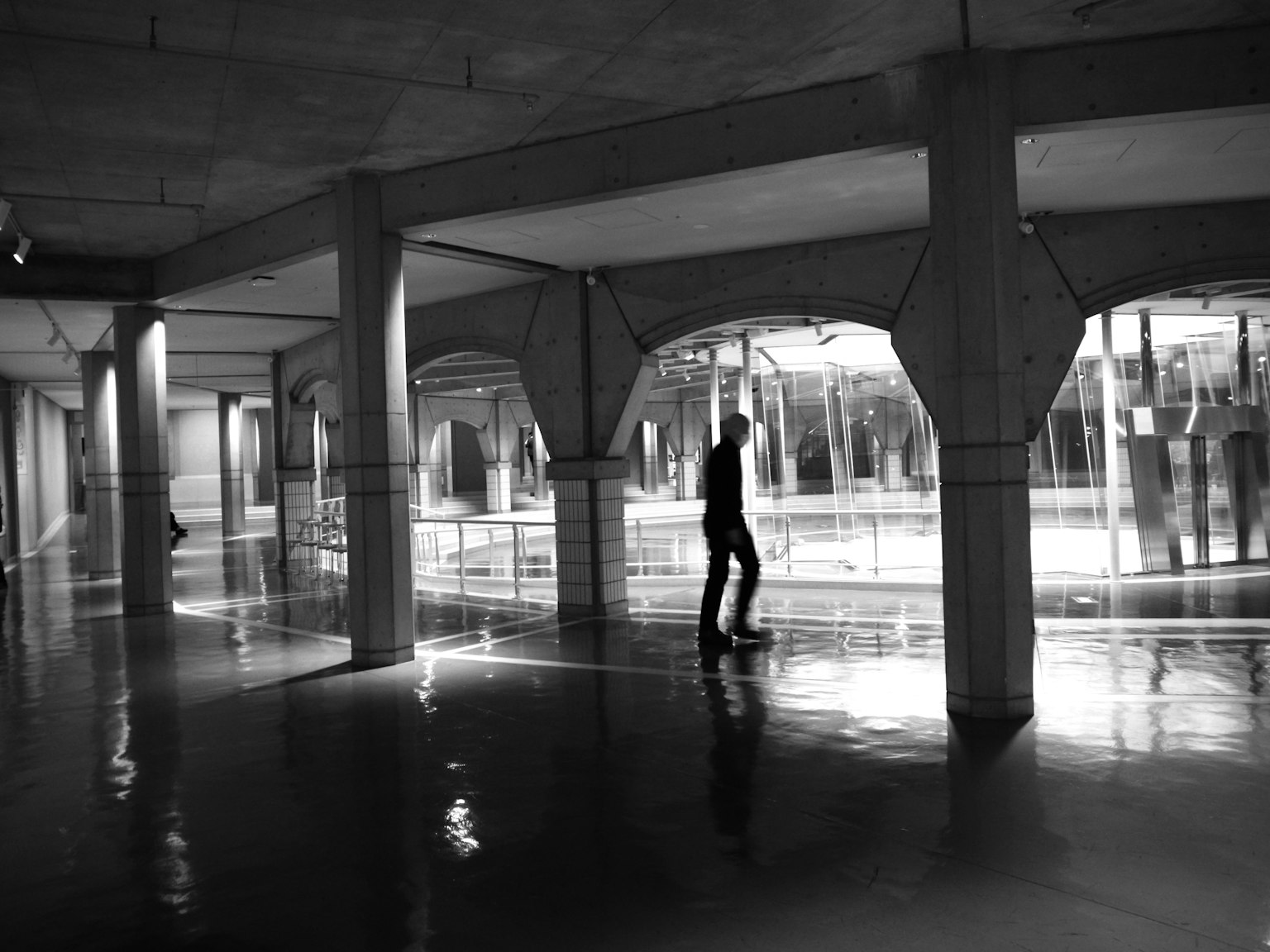 Silhouette einer Person in einem monochromen Untergrundraum mit Reflexionen