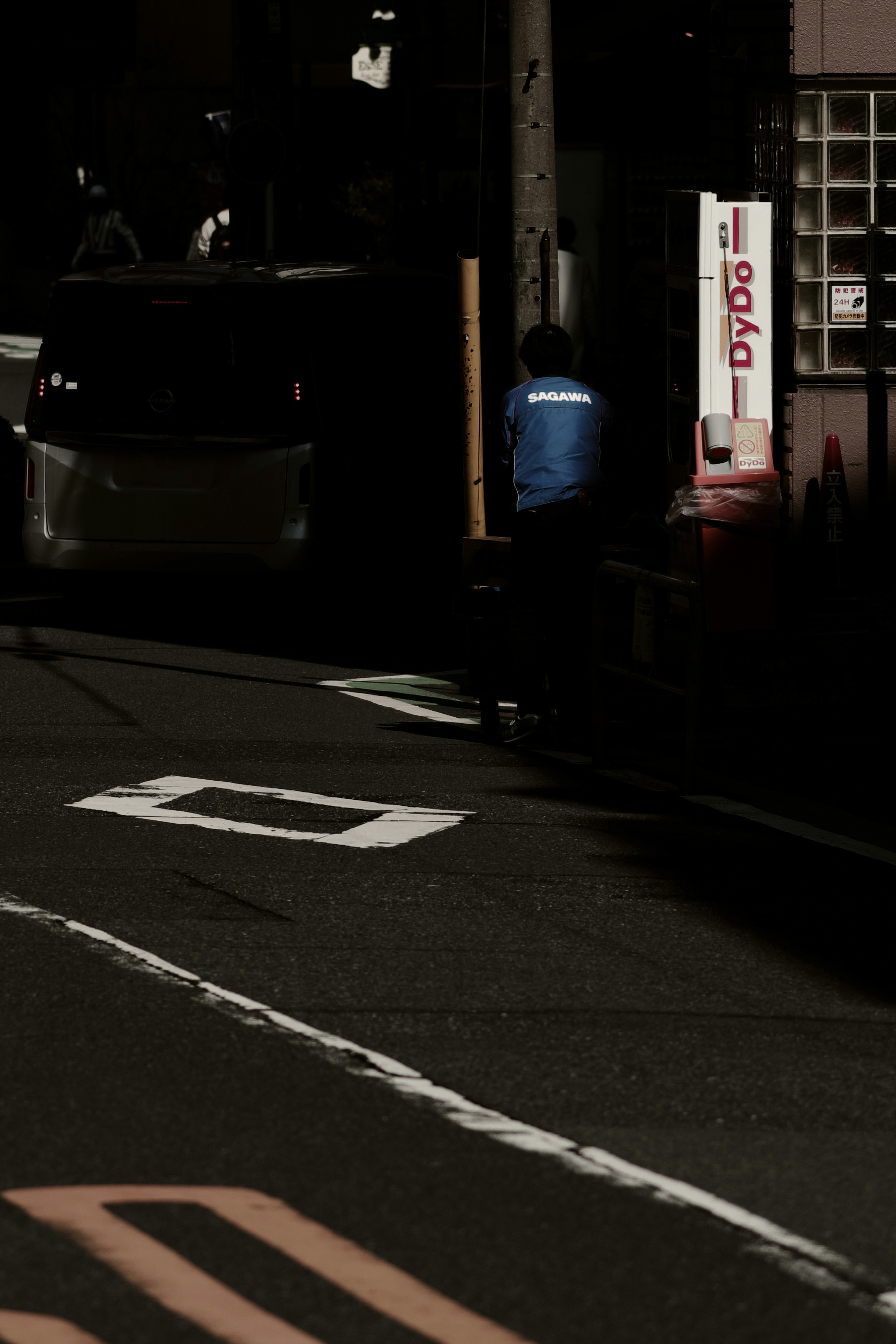 路地の夜に停車するトラックとDyDoの看板のある街並み