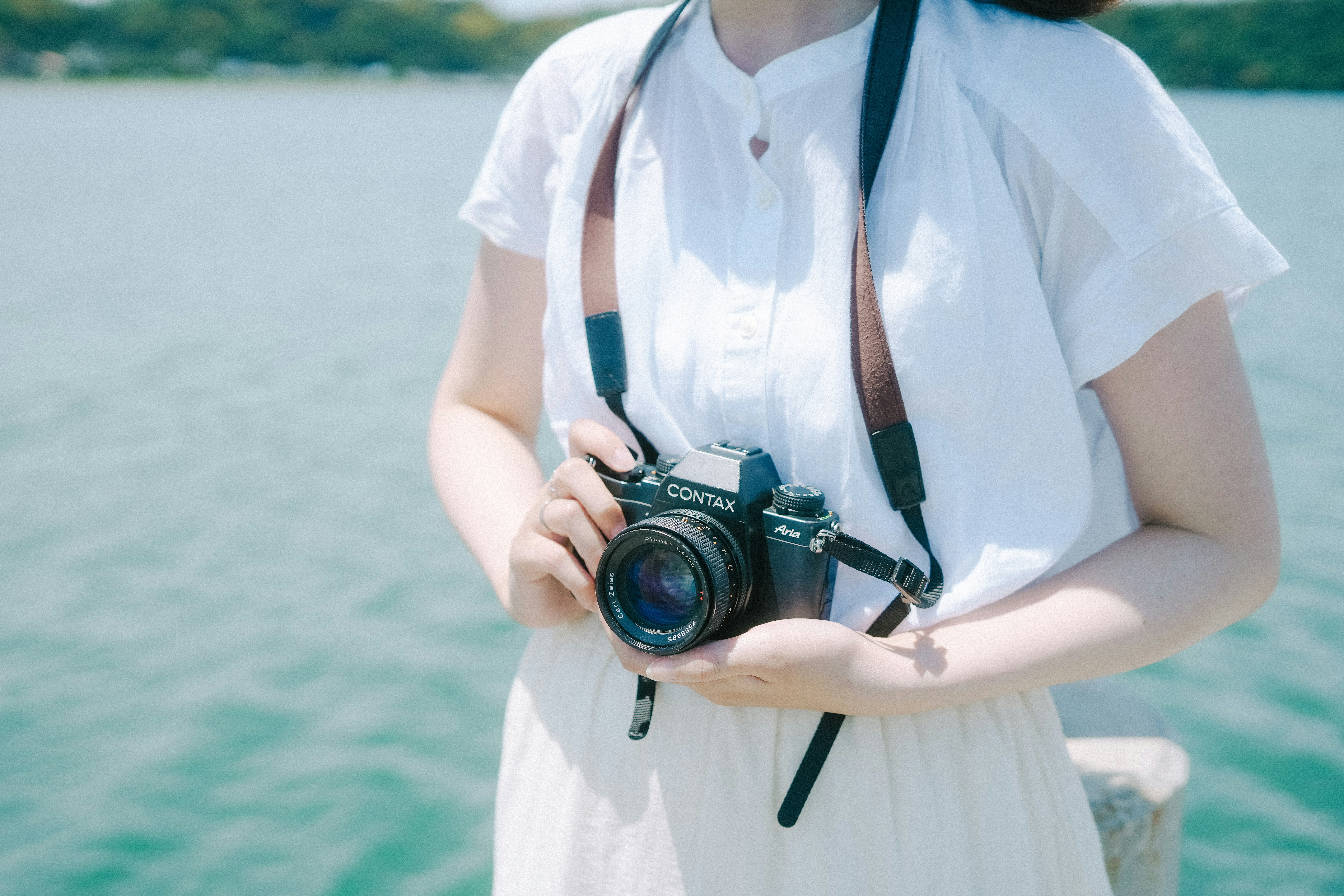 海辺でカメラを持つ女性の上半身