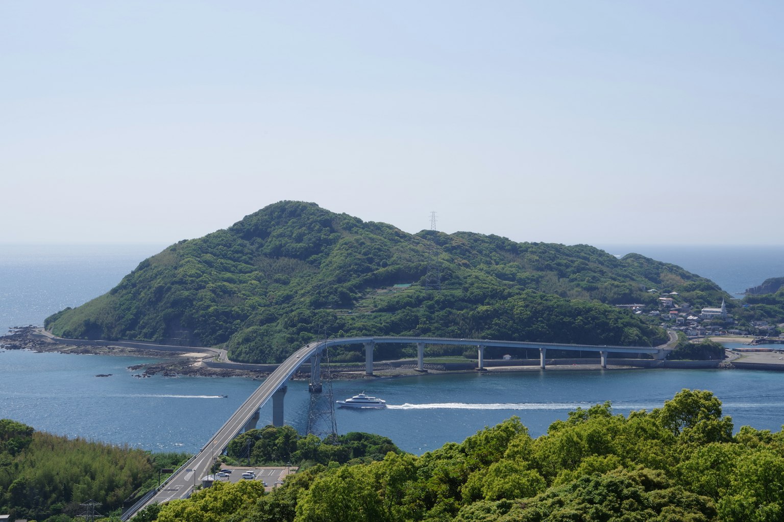 Scenic view of an island with green hills and a bridge over blue water