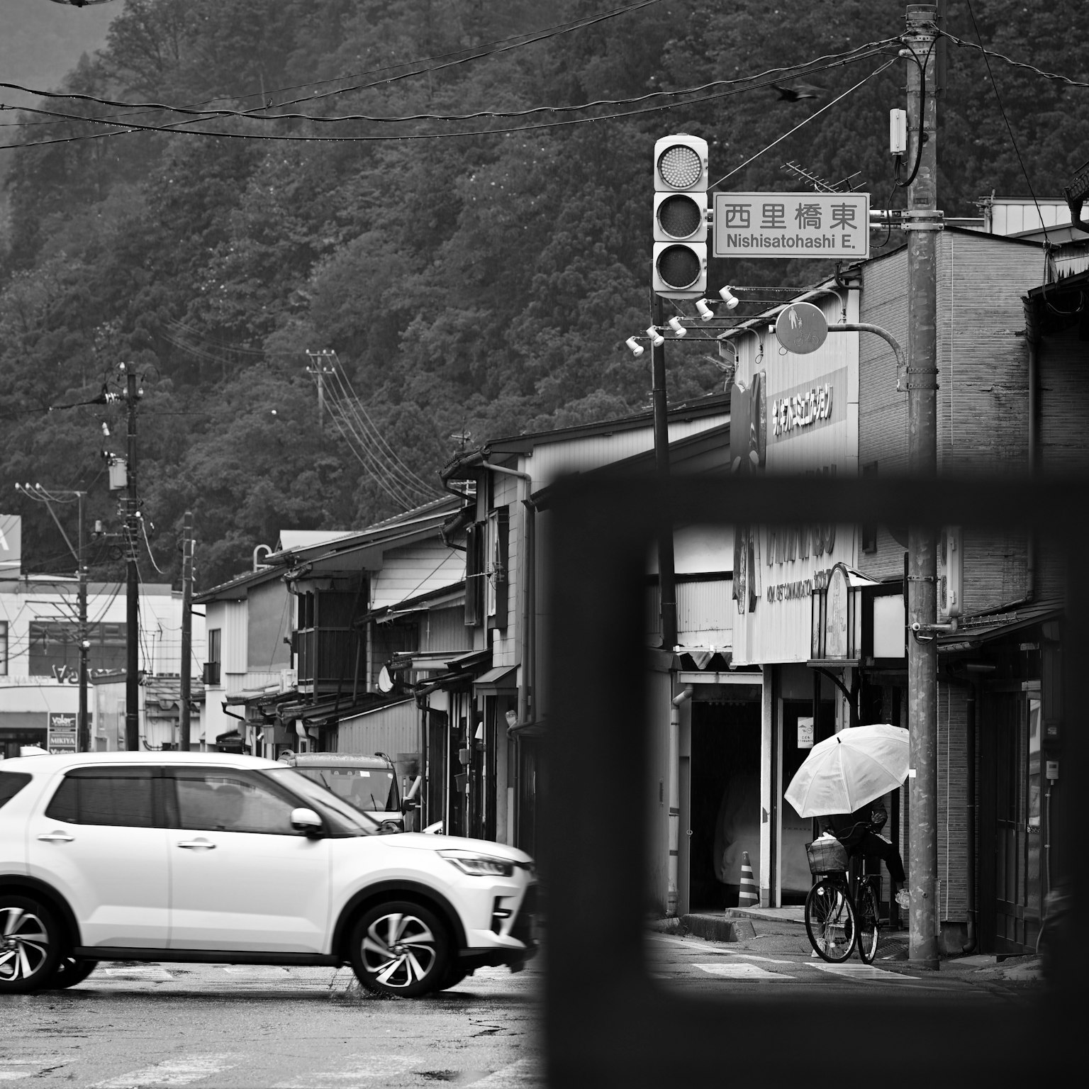 白黒の街角にある信号機と自動車 自転車に乗った人が傘をさしている