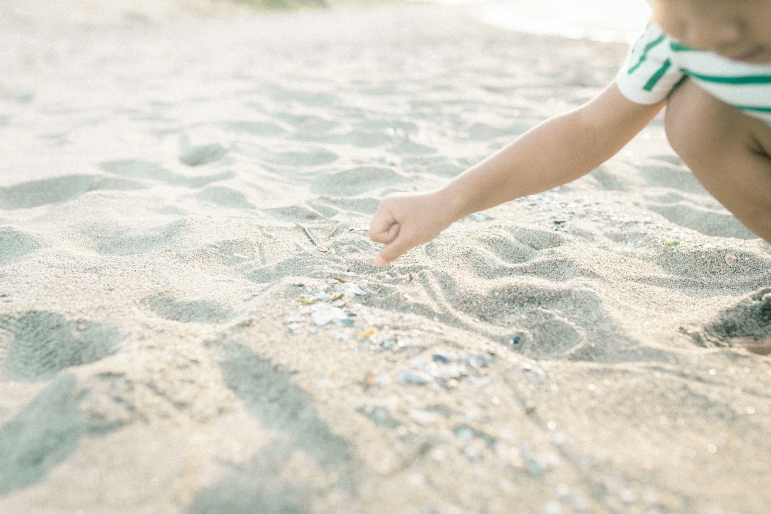 Mano de un niño tocando la arena en la playa