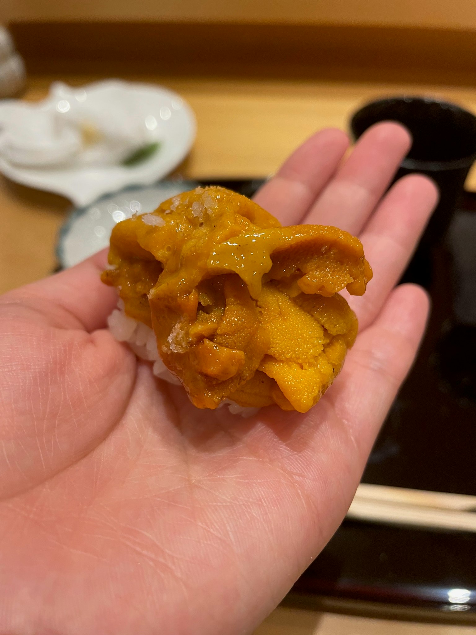 Image de sushi d'oursin tenu dans une main