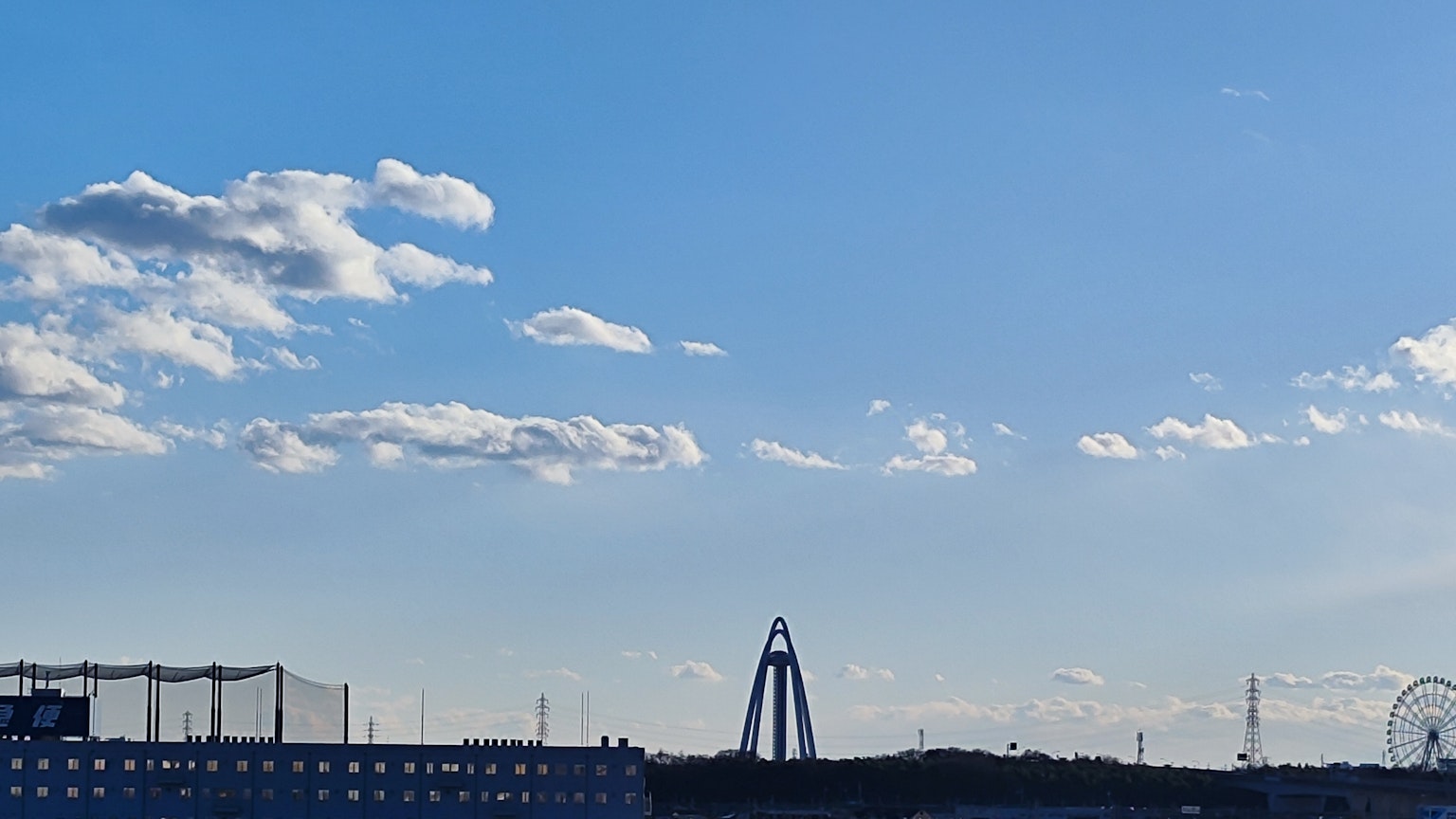Eine malerische Aussicht mit blauem Himmel und Wolken, die ein Riesenrad zeigt