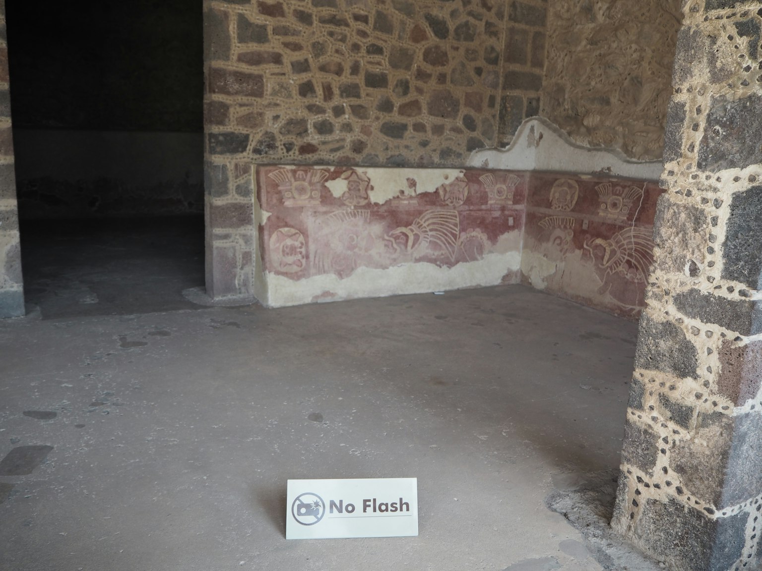 ภายในห้องหินโบราณที่มีการตกแต่งผนังสีแดงที่จางหาย