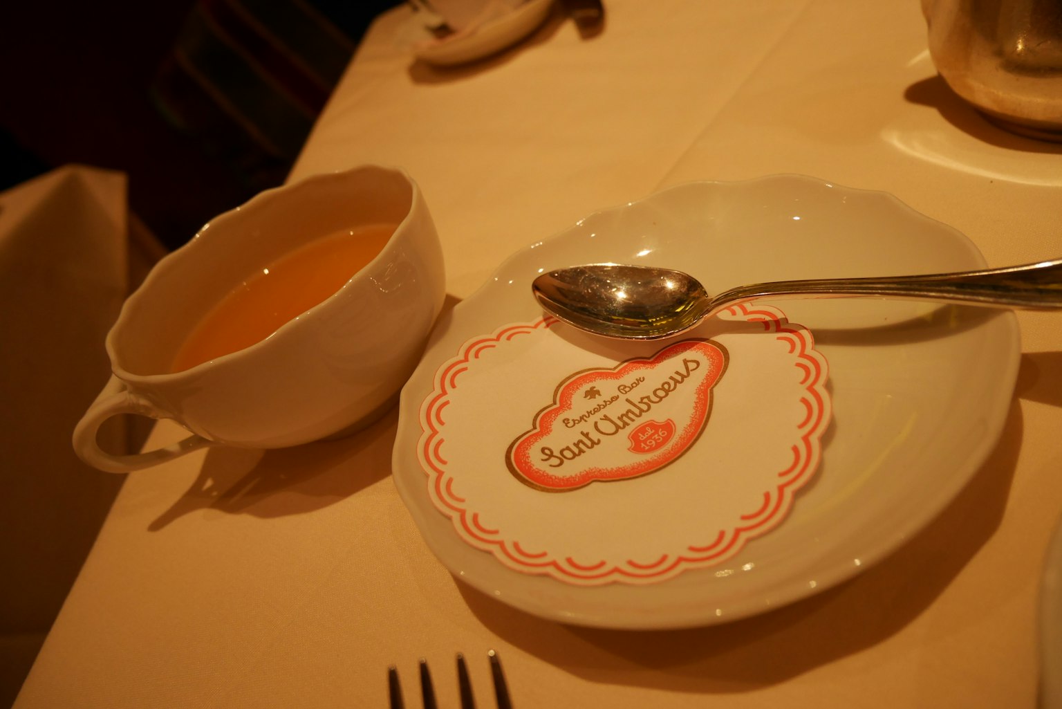 Un plato de sopa con una cuchara en una mesa con un diseño rojo en el plato