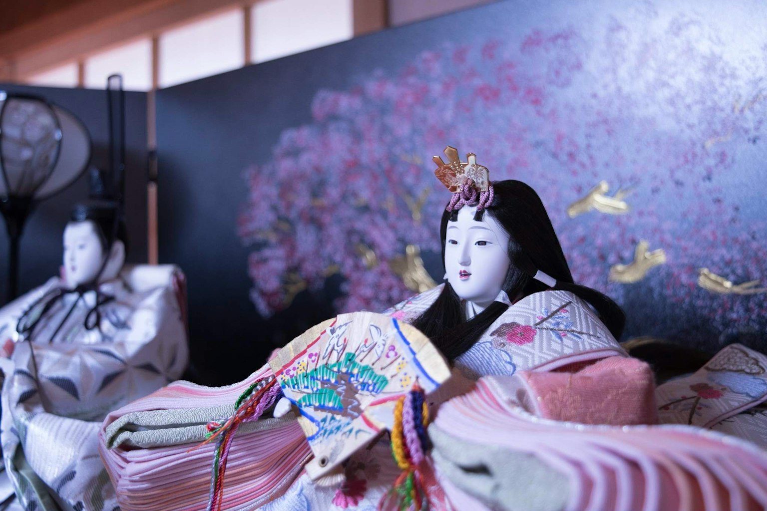Beautiful display of hina dolls with colorful fabric decorations in the background