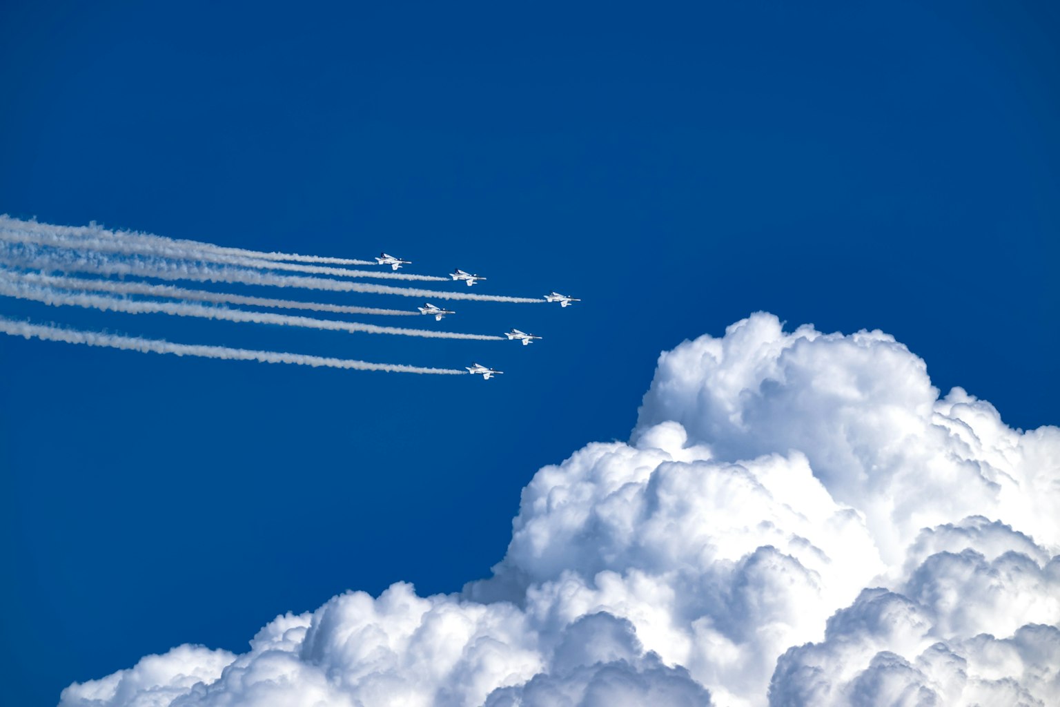 青空に白い雲と飛行機の煙 trailsが描かれた画像