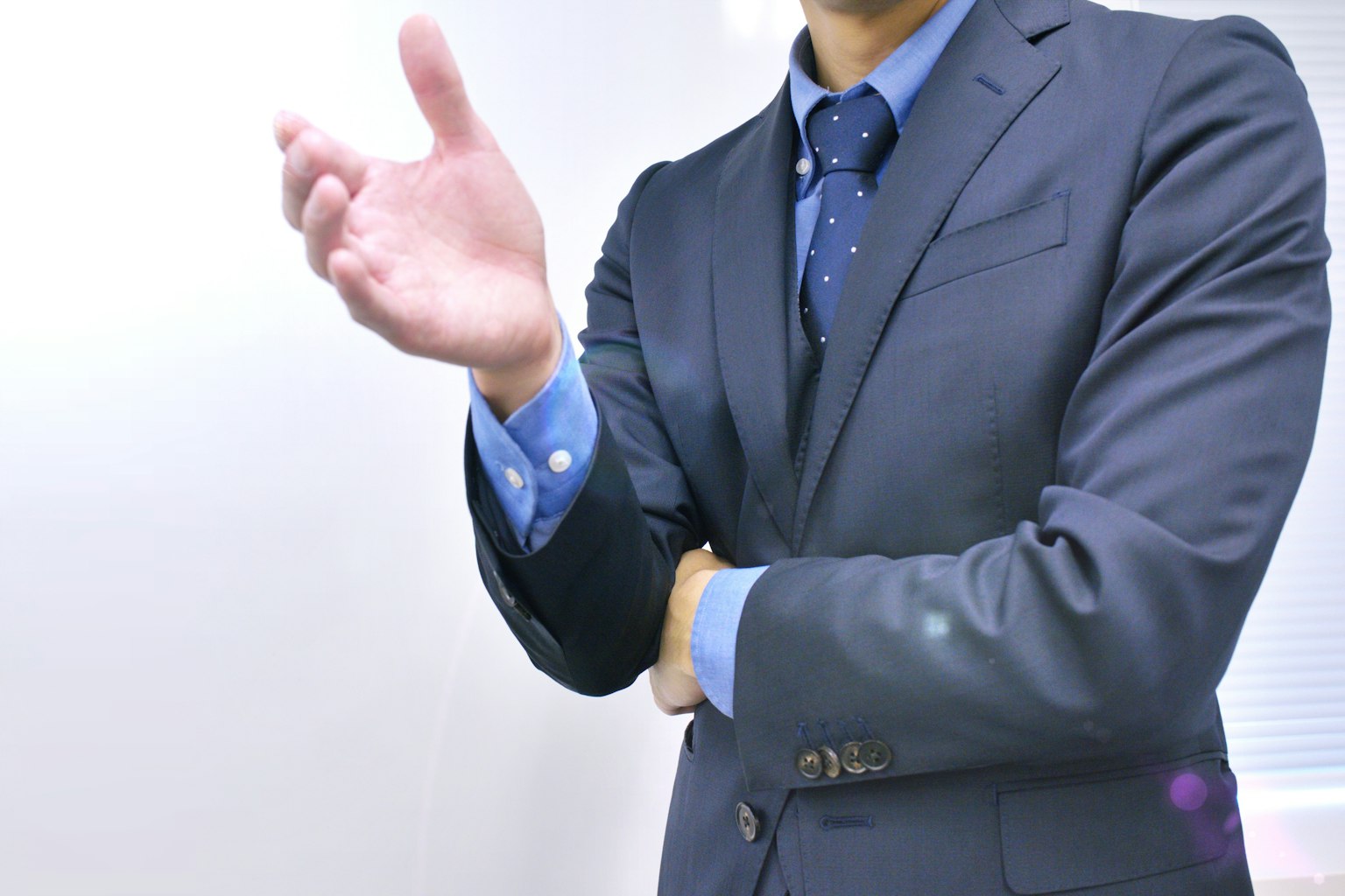 A business-suited man gesturing with his hand in a speaking pose