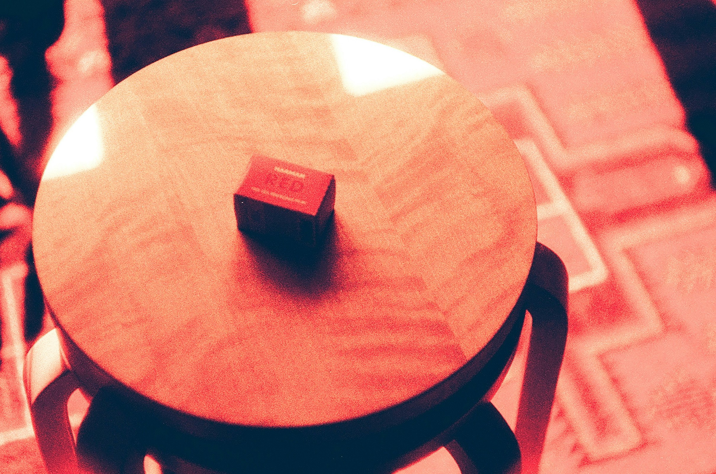 红色灯光下写着“RED”的盒子放在圆桌上