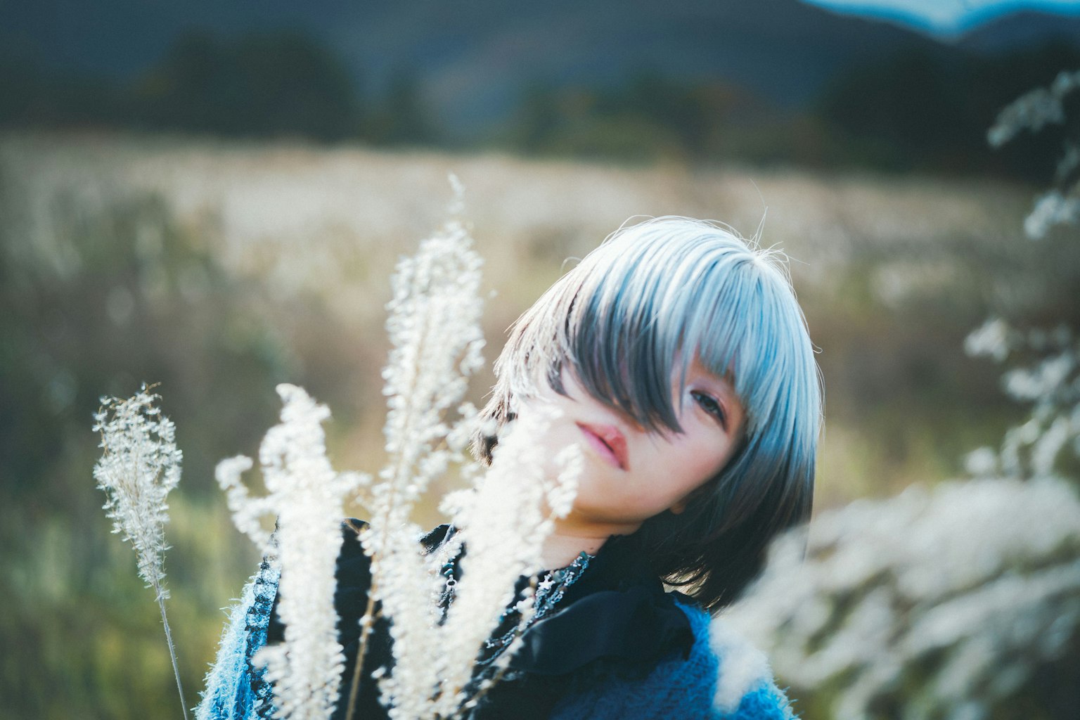 一位藍髮女性在風景中手持白色植物