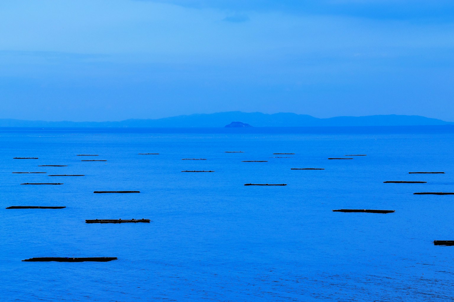 A serene blue sea and sky landscape with rectangular structures floating